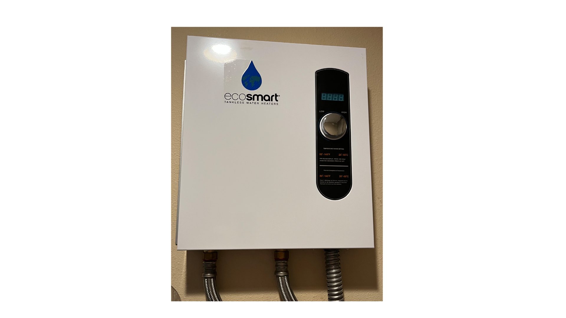 A white EcoSmart tankless water heater with a digital display and control knob, mounted on a beige wall.