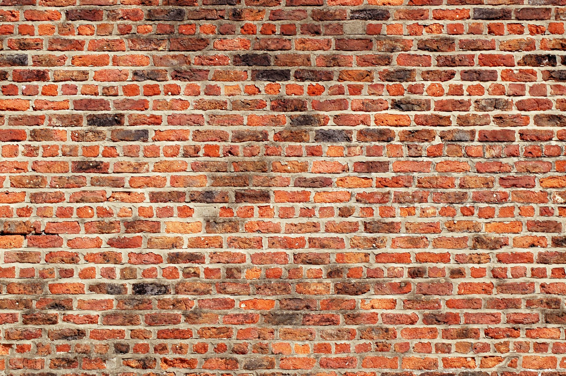 Weathered red brick wall texture with varying shades and mortar lines.