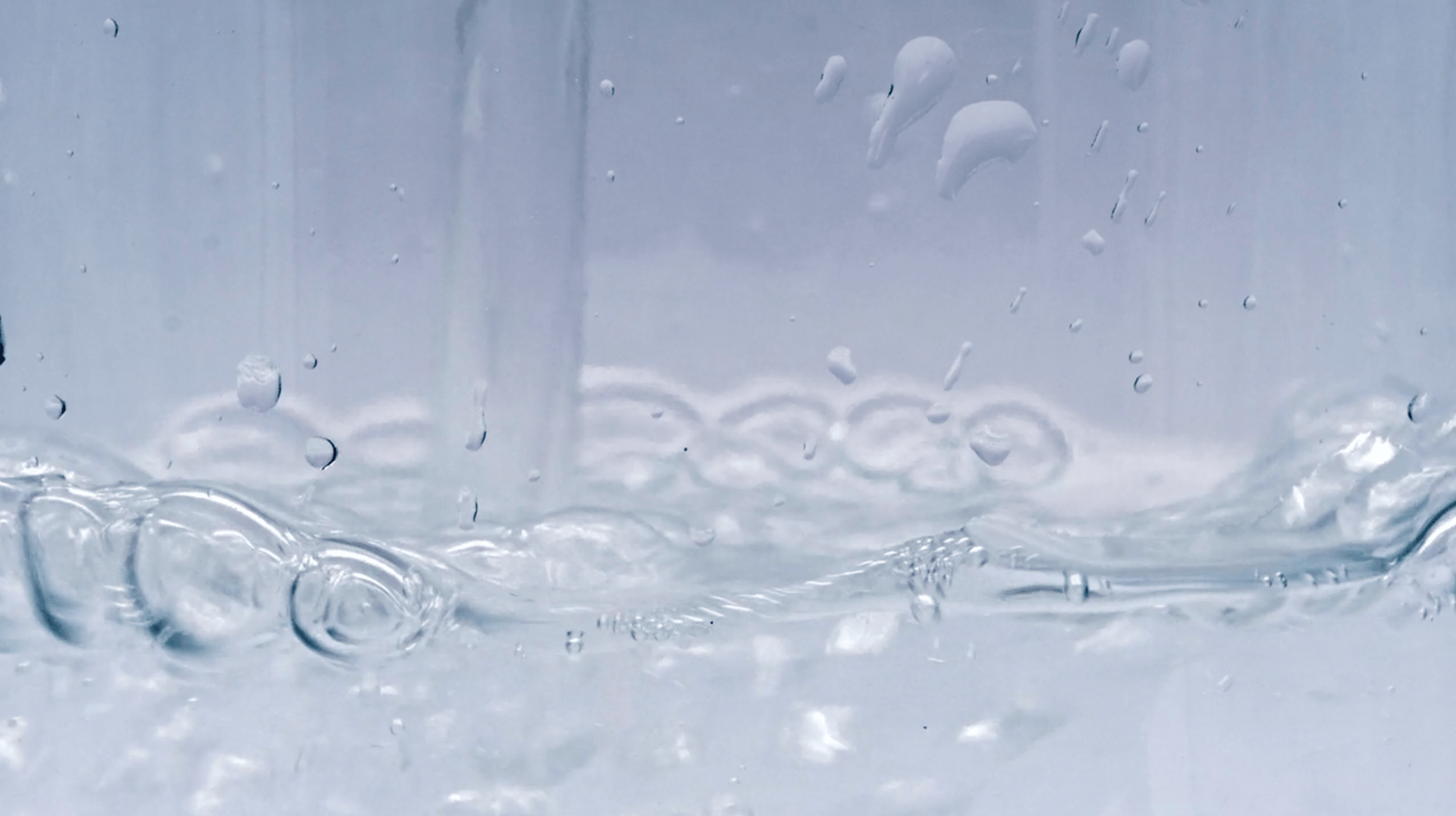 Macro shot of clear water with numerous bubbles, intricate ripples, and a dynamic surface.
