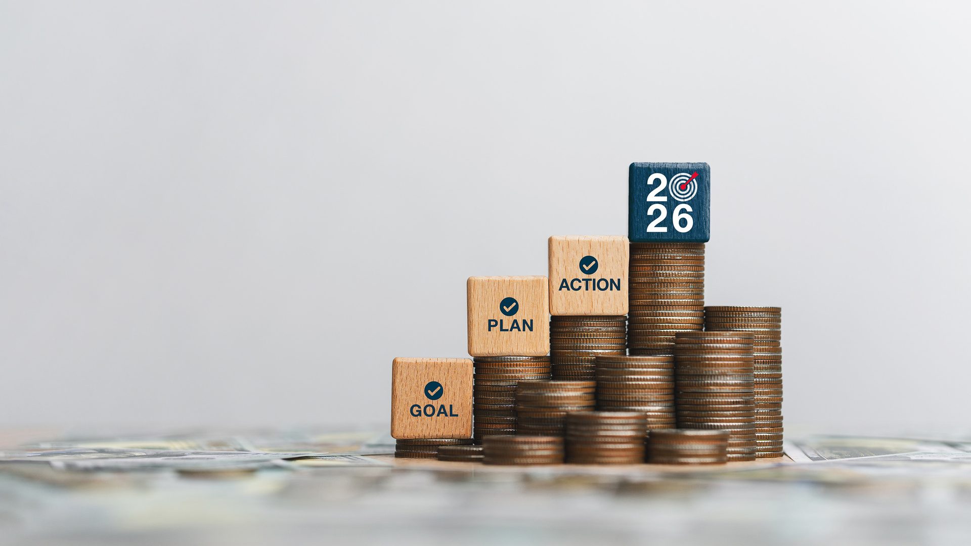 Stacks of coins with blocks: GOAL, PLAN, ACTION, and a 2026 target block.