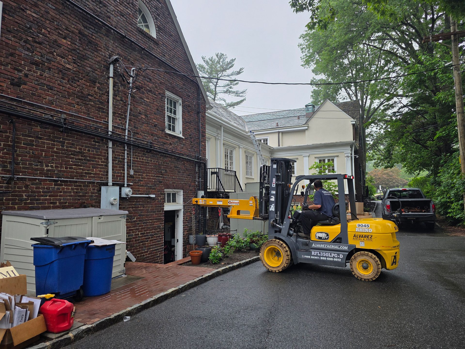 Forklift with boom attachment lifting item towards building.