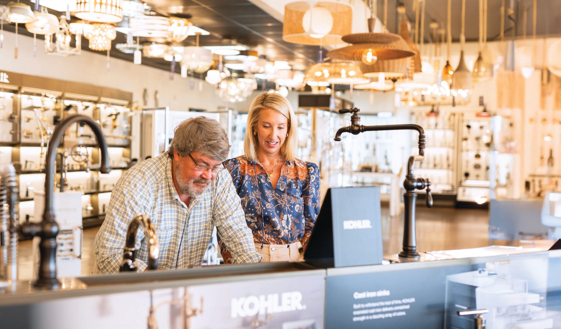 A man and a woman looking at faucets and sinks in a Kohler showroom.