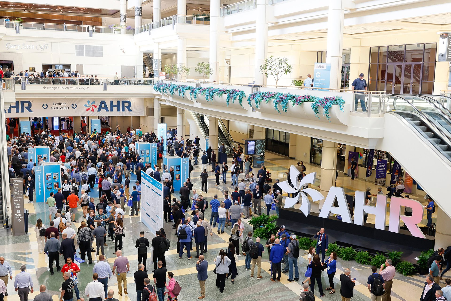 A crowded convention center hall with AHR signs, people, and multiple levels.