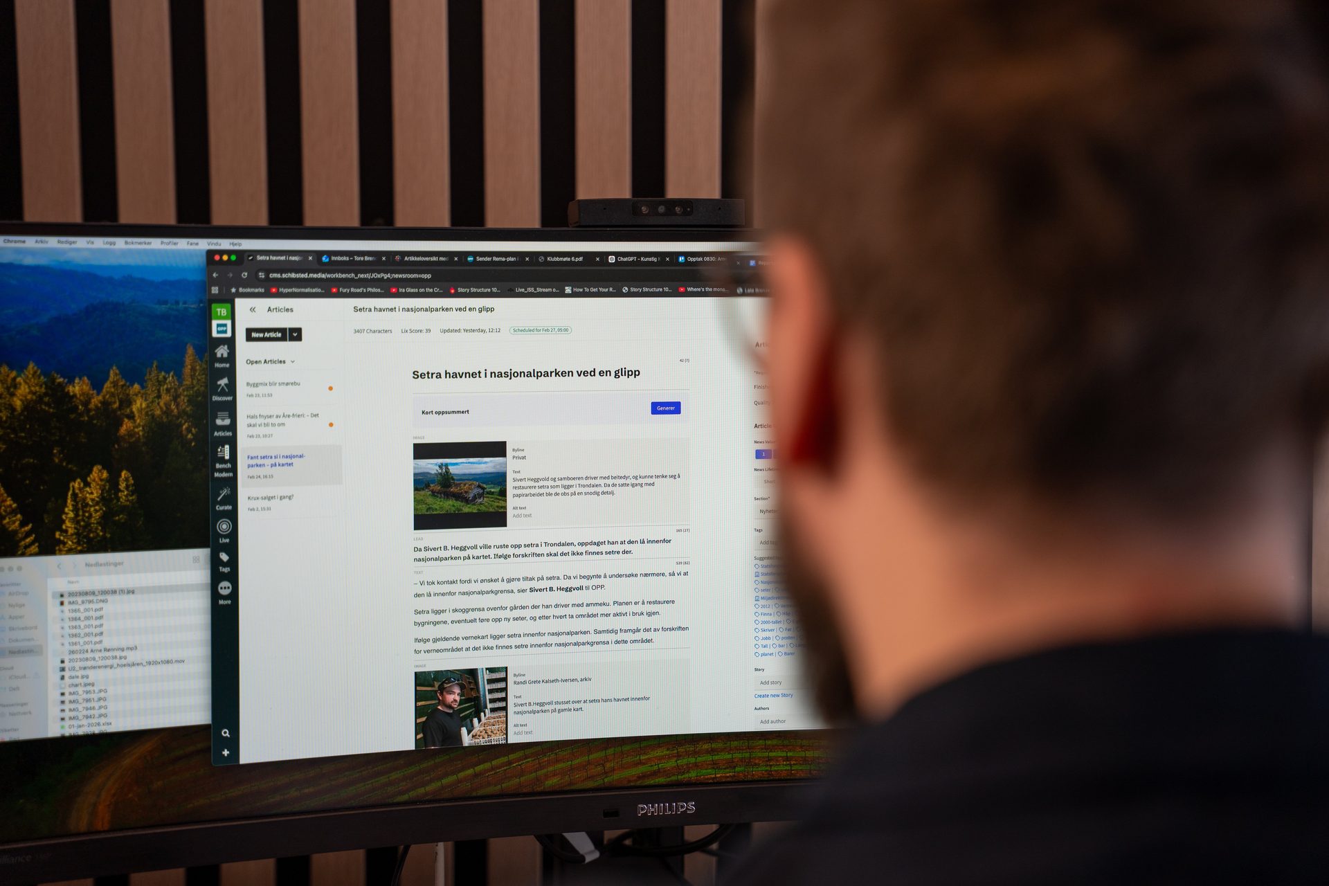 Person views computer monitors, one displaying a Norwegian article about a national park.