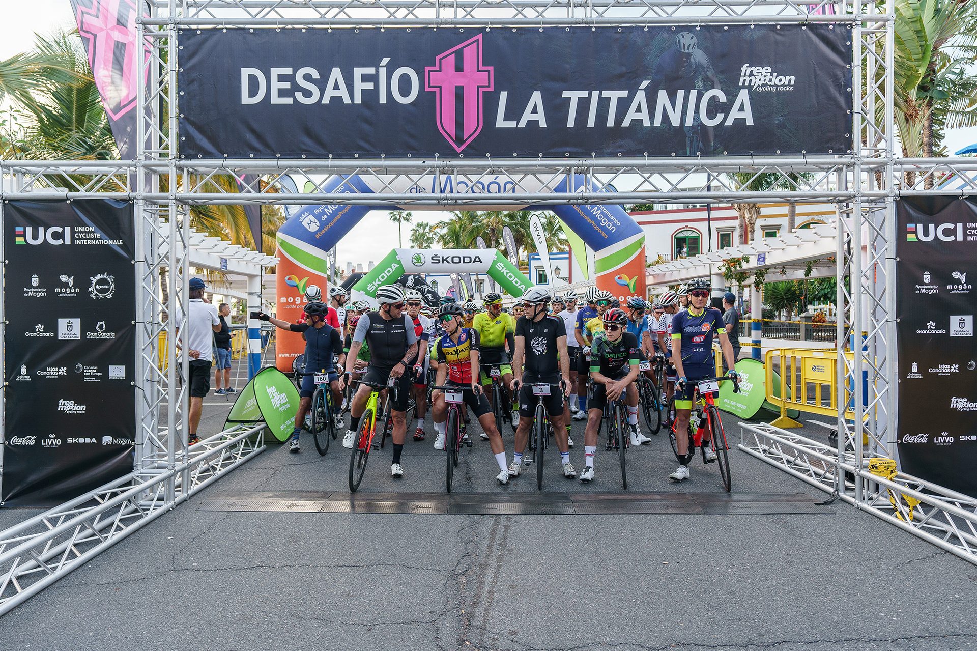 Cyclists at the starting line of the "DESAFÍO LA TITÁNICA" race with sponsor banners.