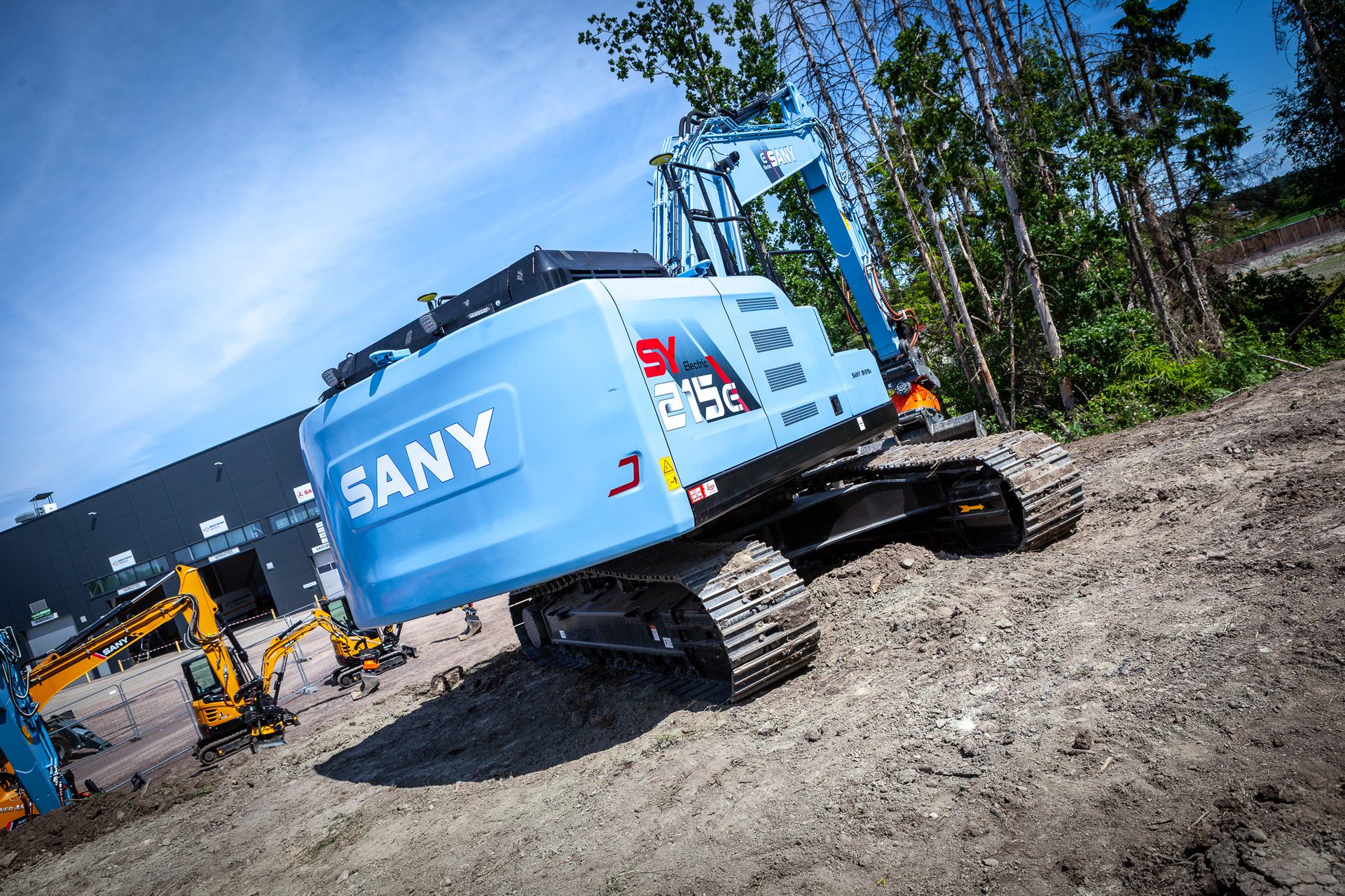 Light blue SANY electric excavator on dirt at a construction site with other machines.