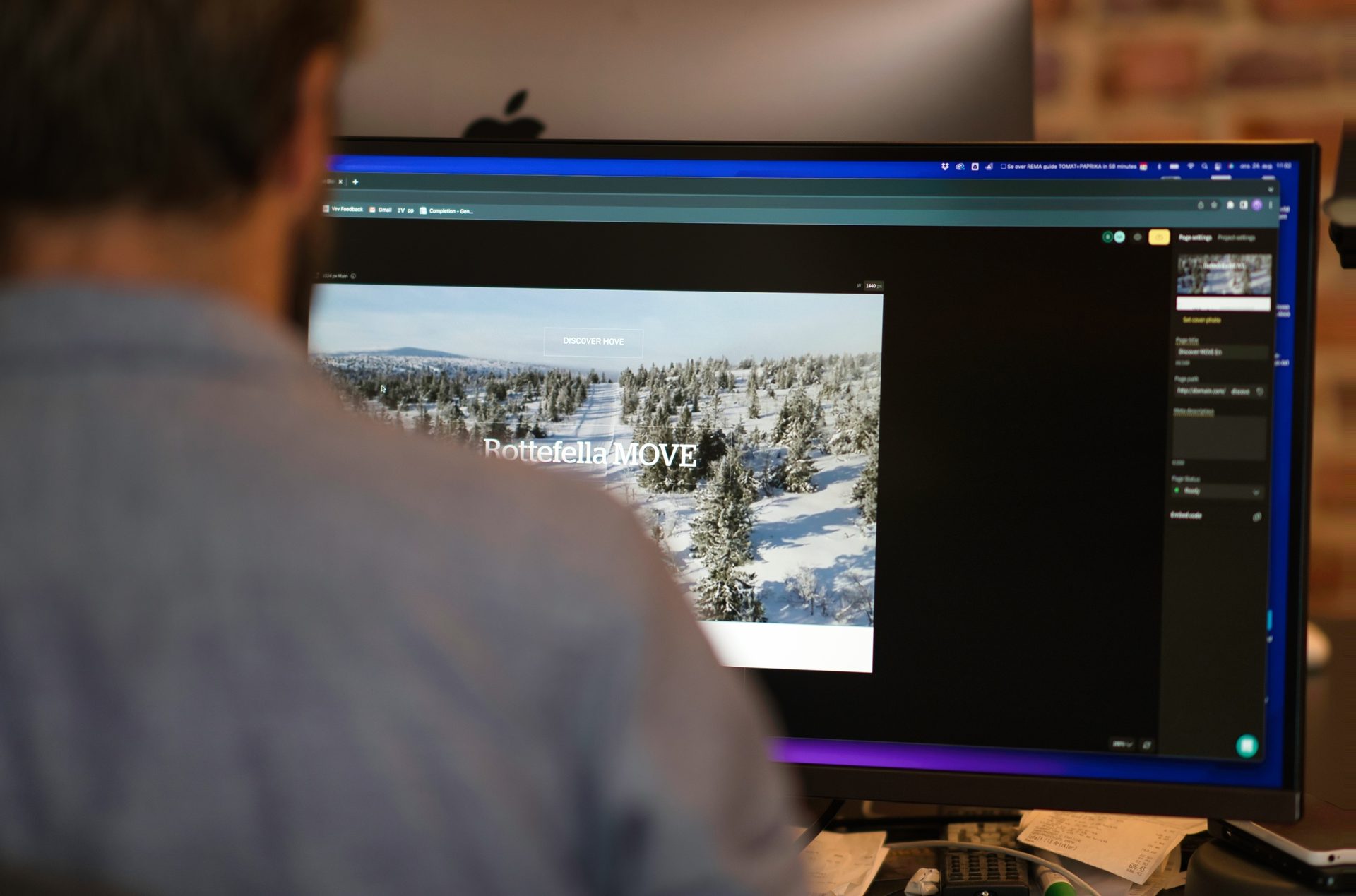 Close-up of a person's back as they work on a computer displaying a website with "Rottefella MOVE".