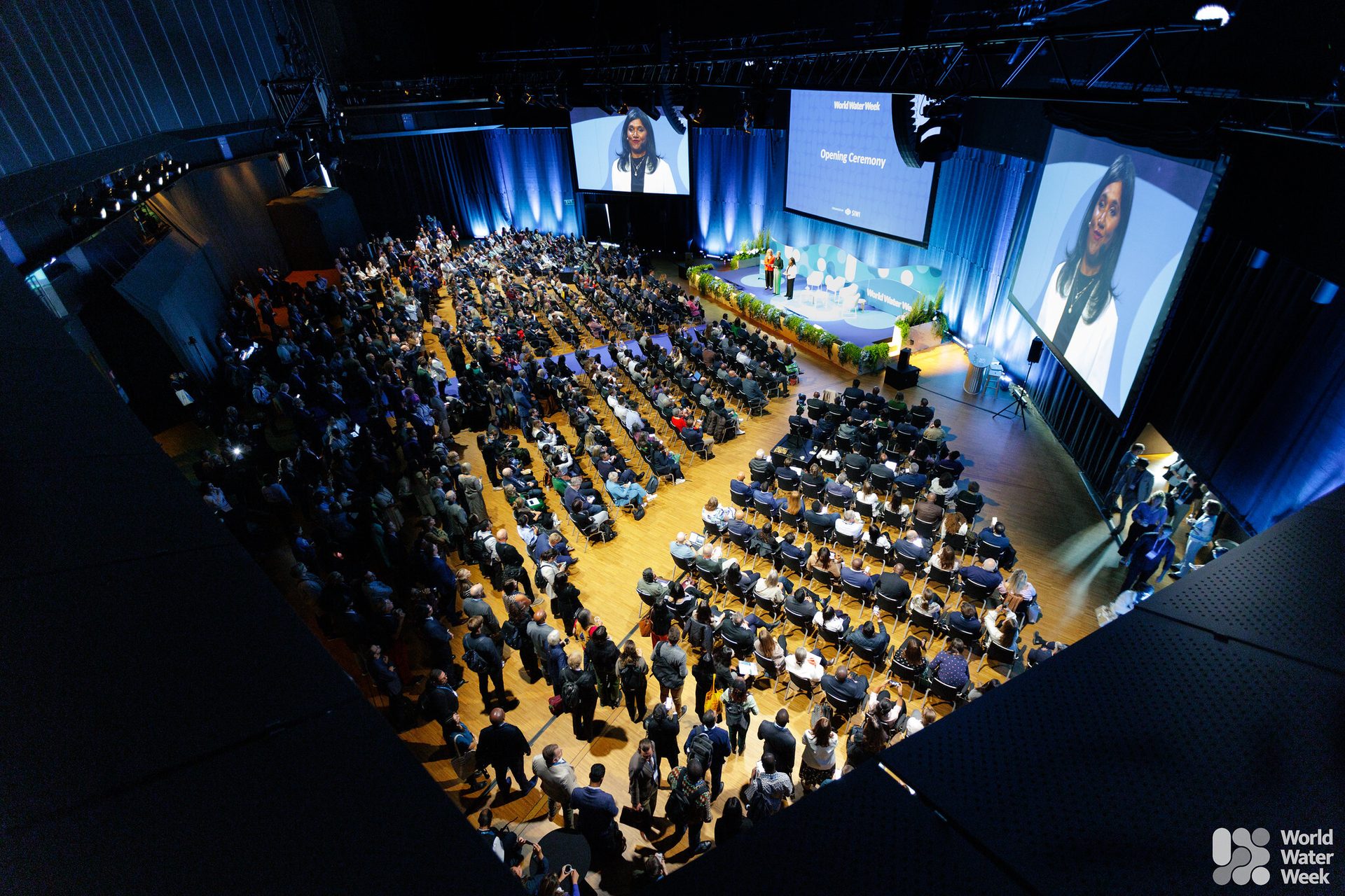World Water Week opening ceremony: audience, stage with screens, and a speaker.