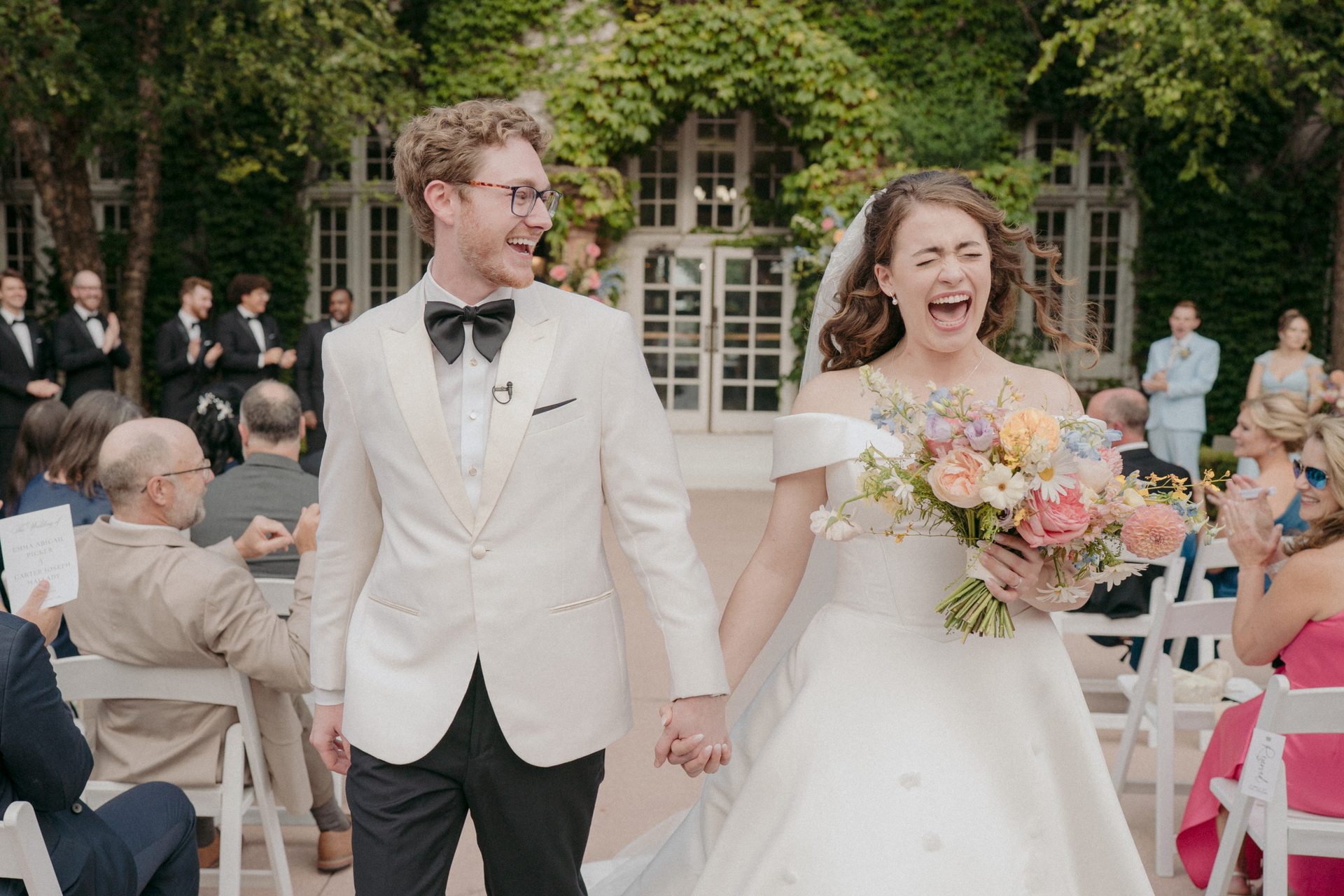 Joyful bride and groom holding hands, walking down the aisle at their wedding.