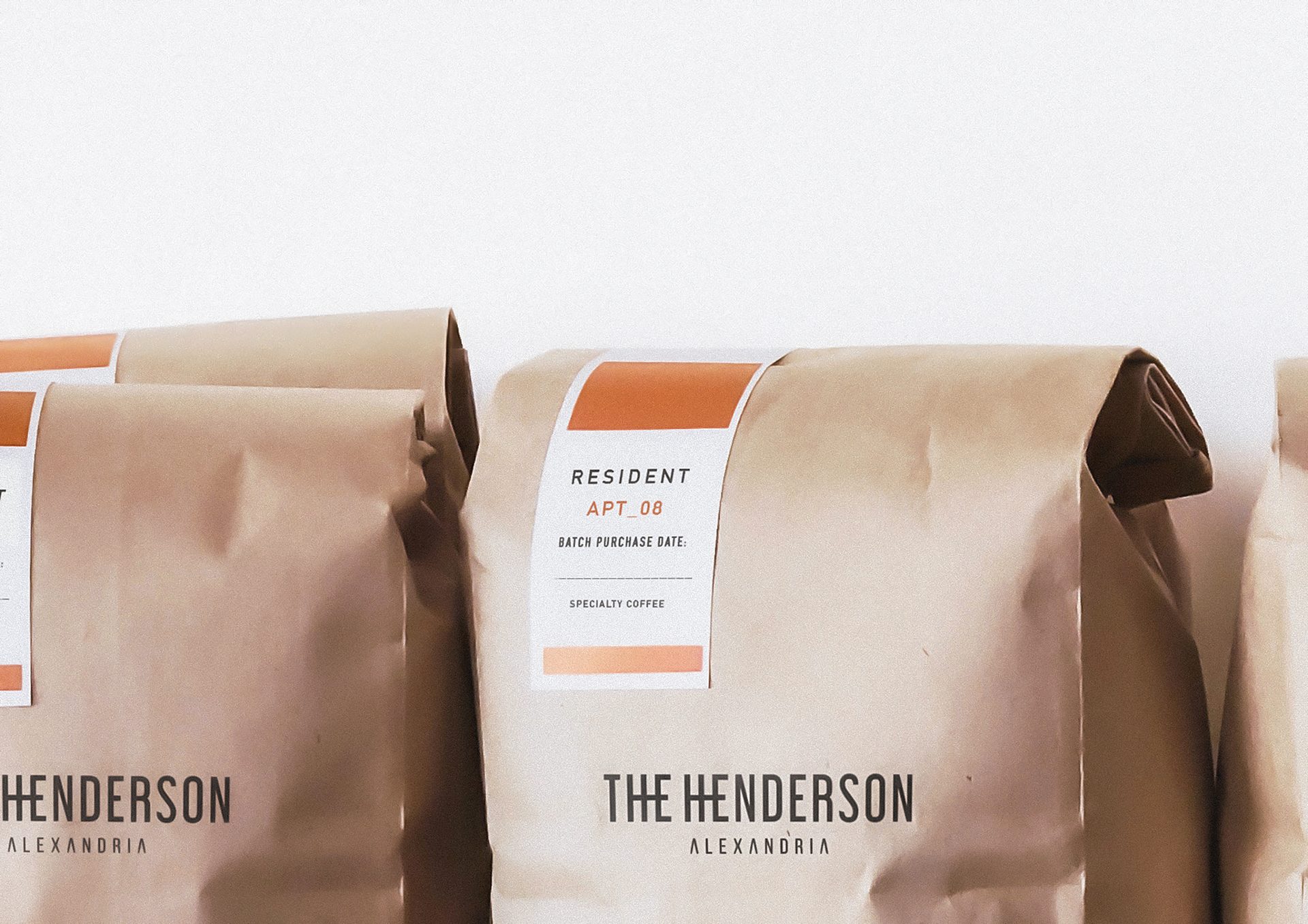 Kraft paper coffee bags with minimalist labels, including "The Henderson" and "Specialty Coffee".
