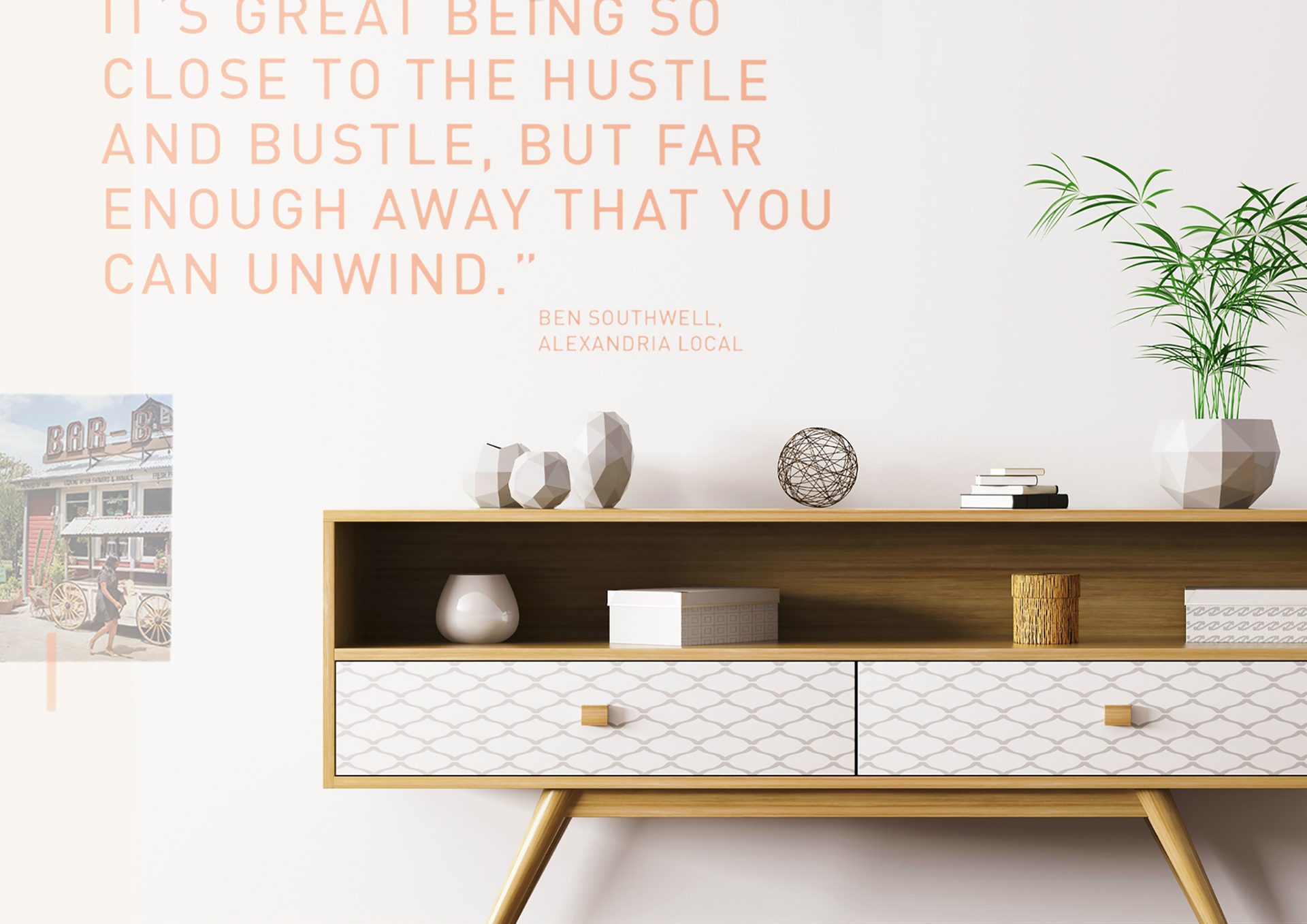 Wall with an orange quote about unwinding above a modern wooden console table with decor and a plant.