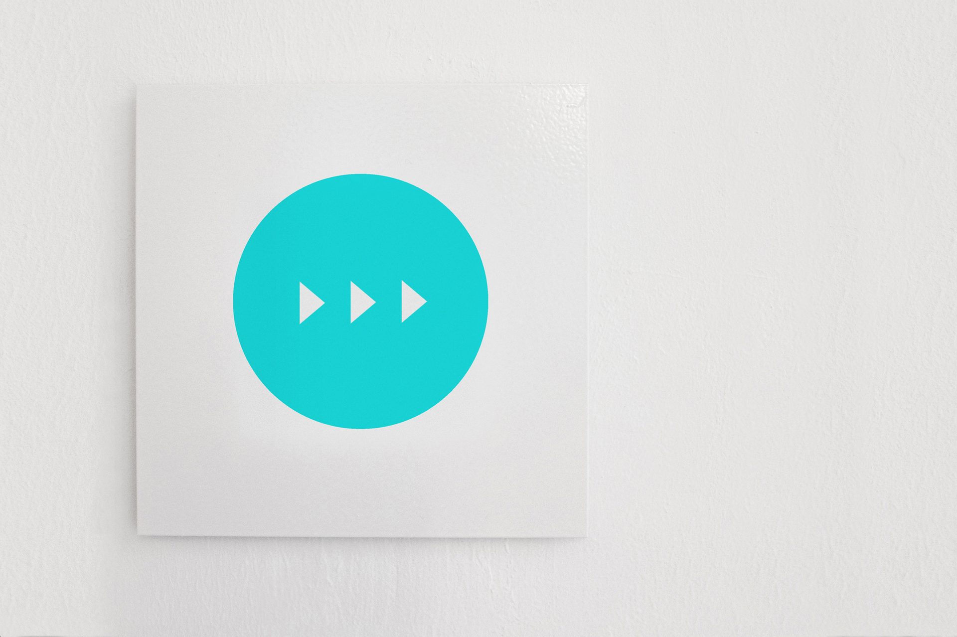 White square on white wall, turquoise circle with three white right arrows.
