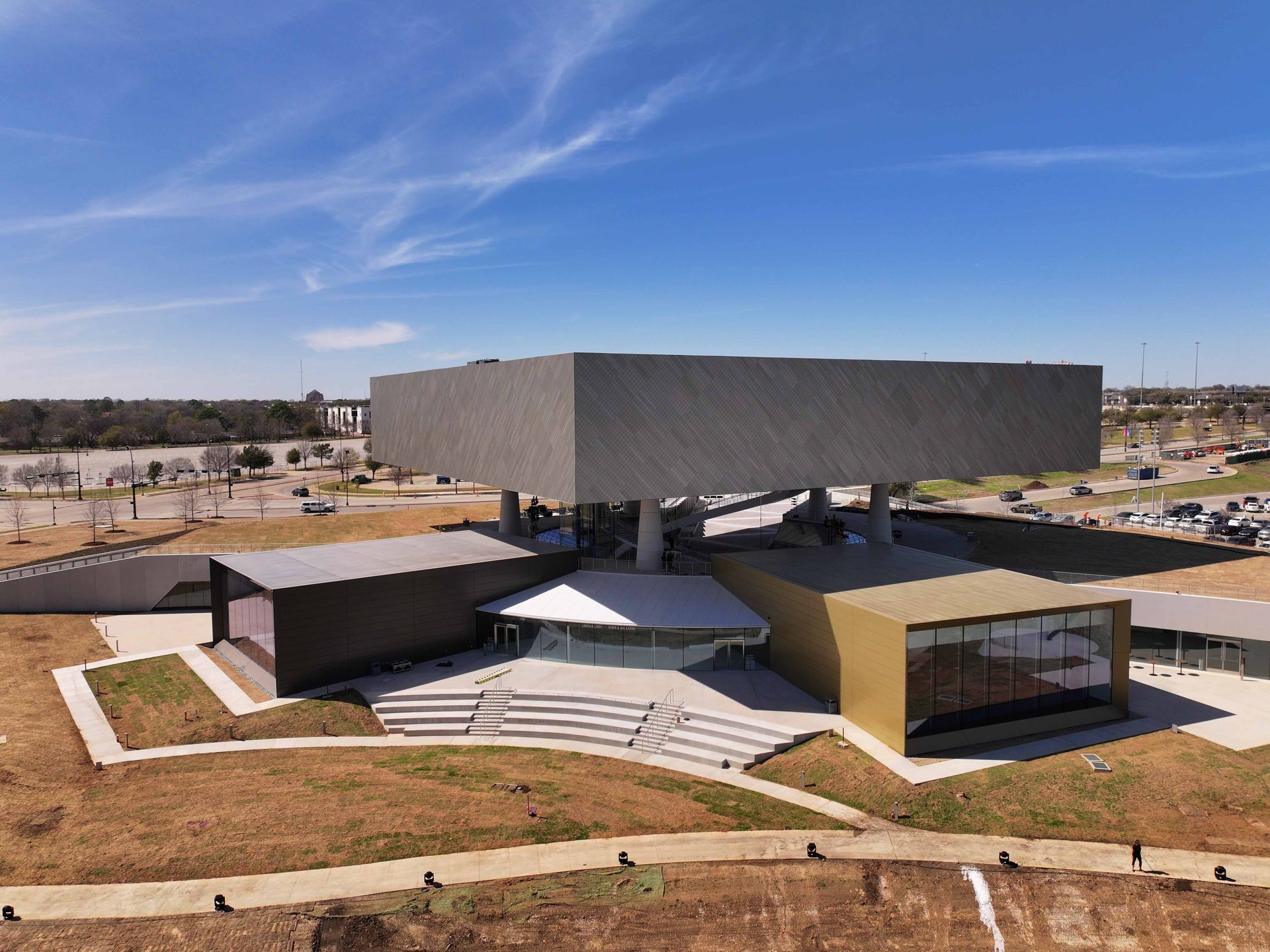 Aerial view of a modern, multi-level building with a large rectangular top section on a clear day.
