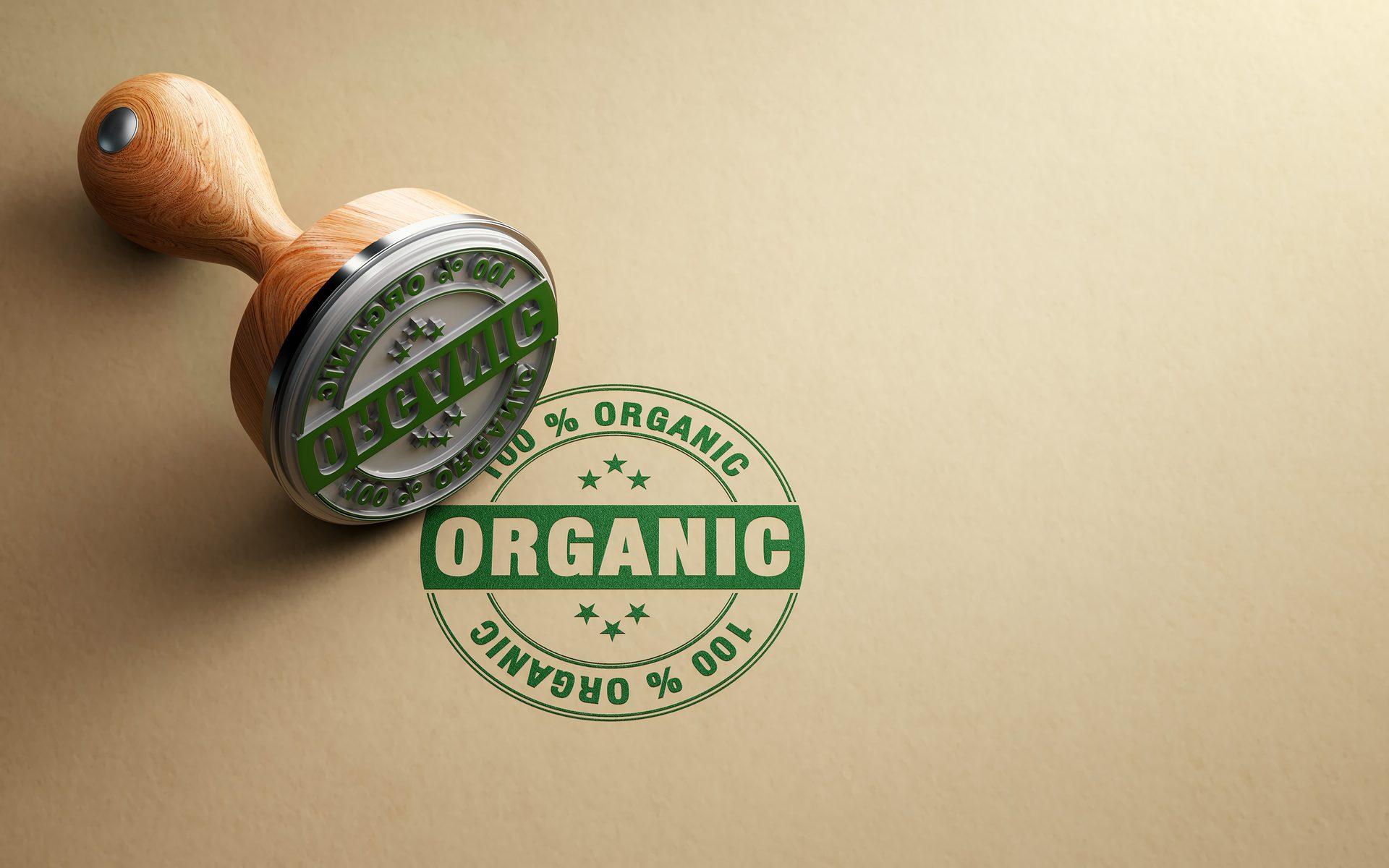 Wooden stamp with "100% ORGANIC" message in green ink on a light brown surface.