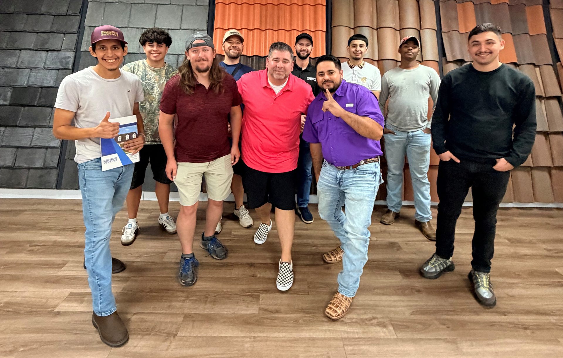 A group of diverse men smiling and posing for a photo in front of roof tile displays.