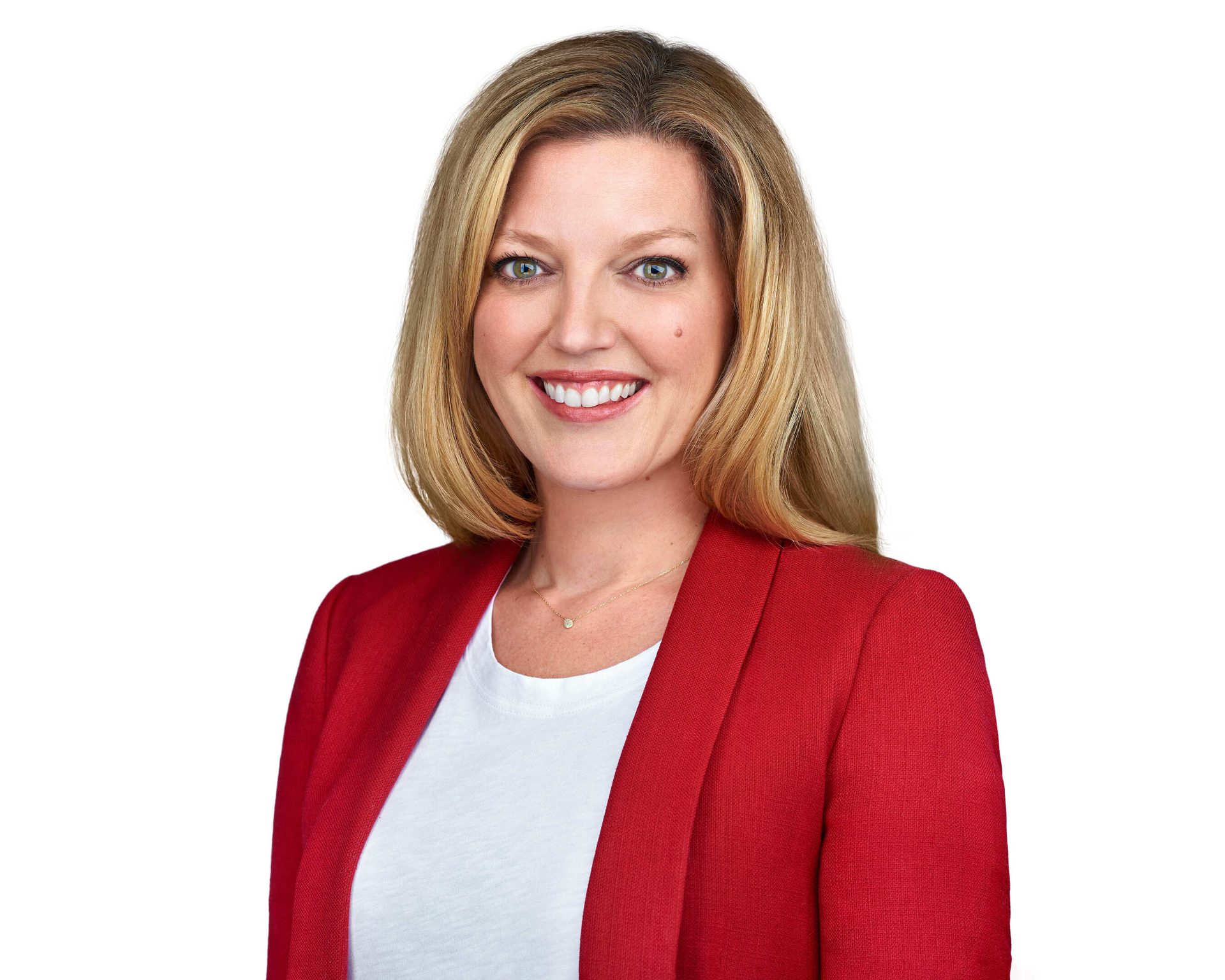 A smiling woman with blonde hair, wearing a red blazer over a white shirt, looking directly at the camera.
