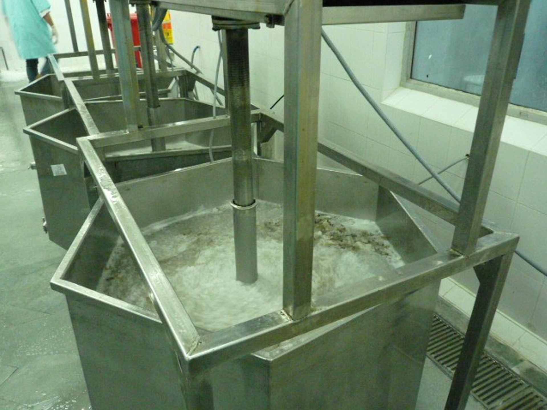 Multiple industrial stainless steel tanks with mixers for processing, one showing foamy agitated contents.