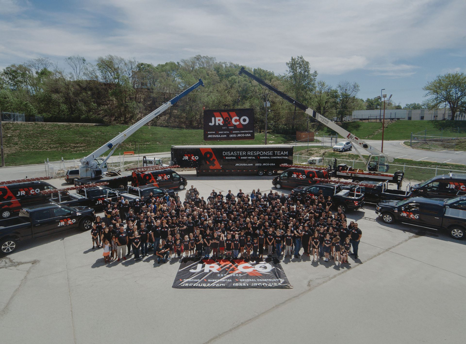Aerial view of JR & CO employees and their construction vehicles, vans, and cranes.