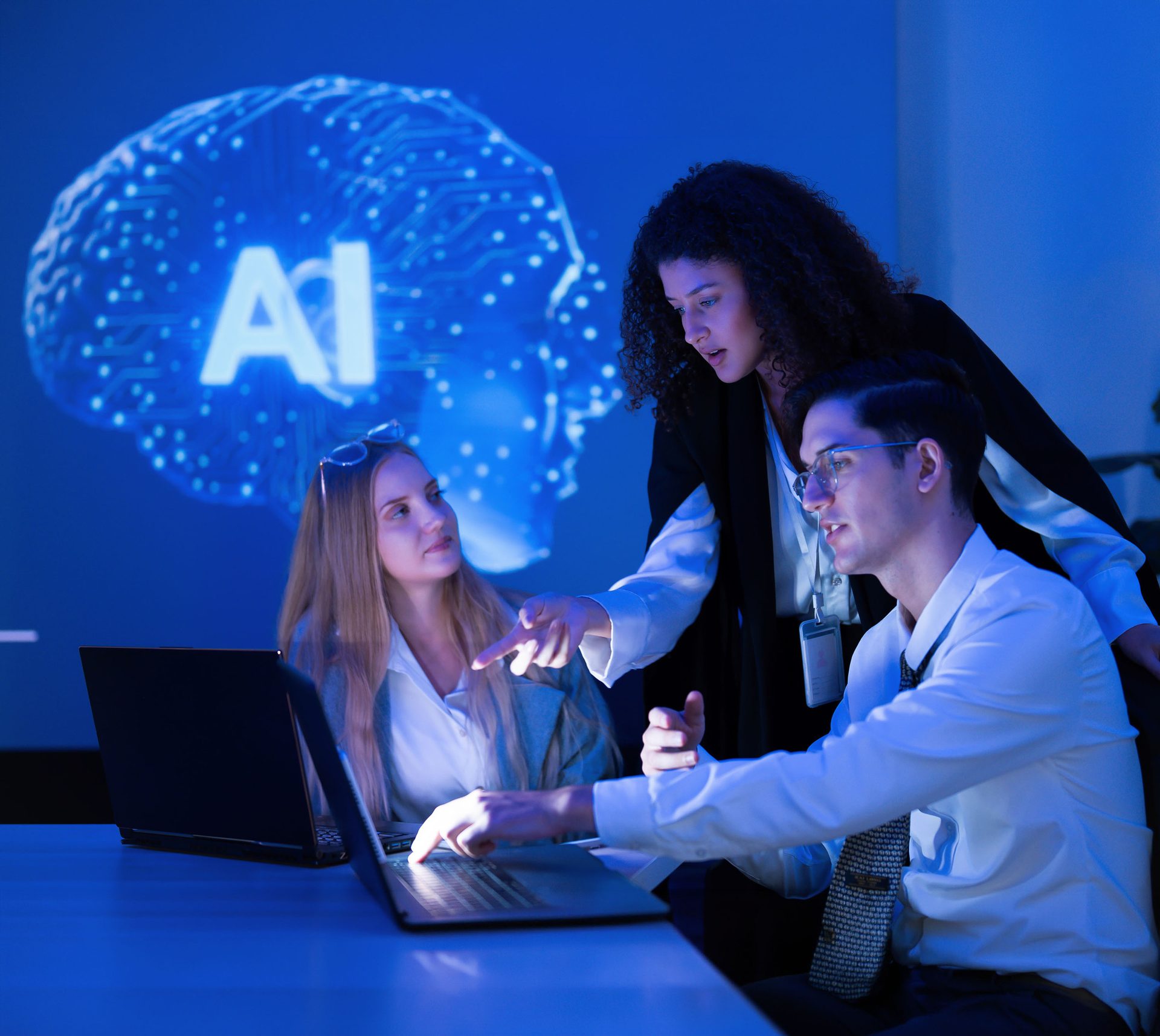 Three diverse professionals collaborating on AI research with laptops in a blue-lit office, with an AI brain projection.