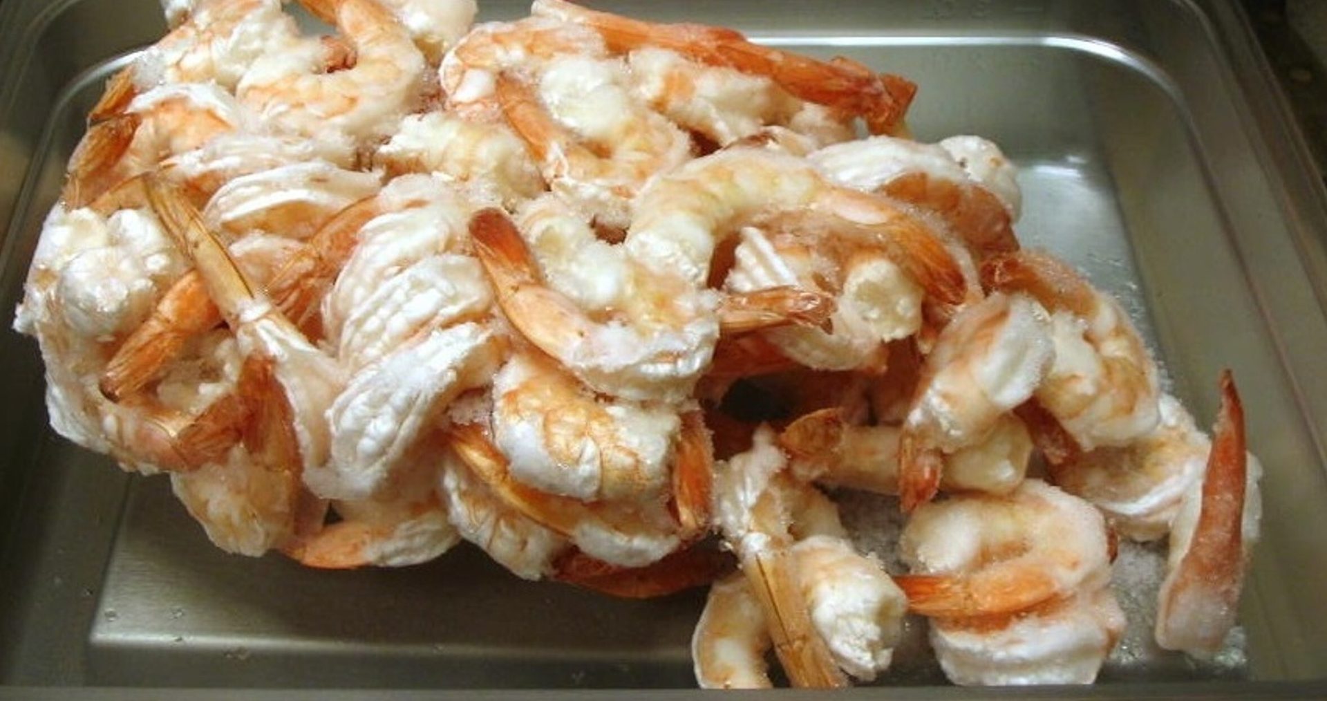 Frozen shrimp in a metal tray.