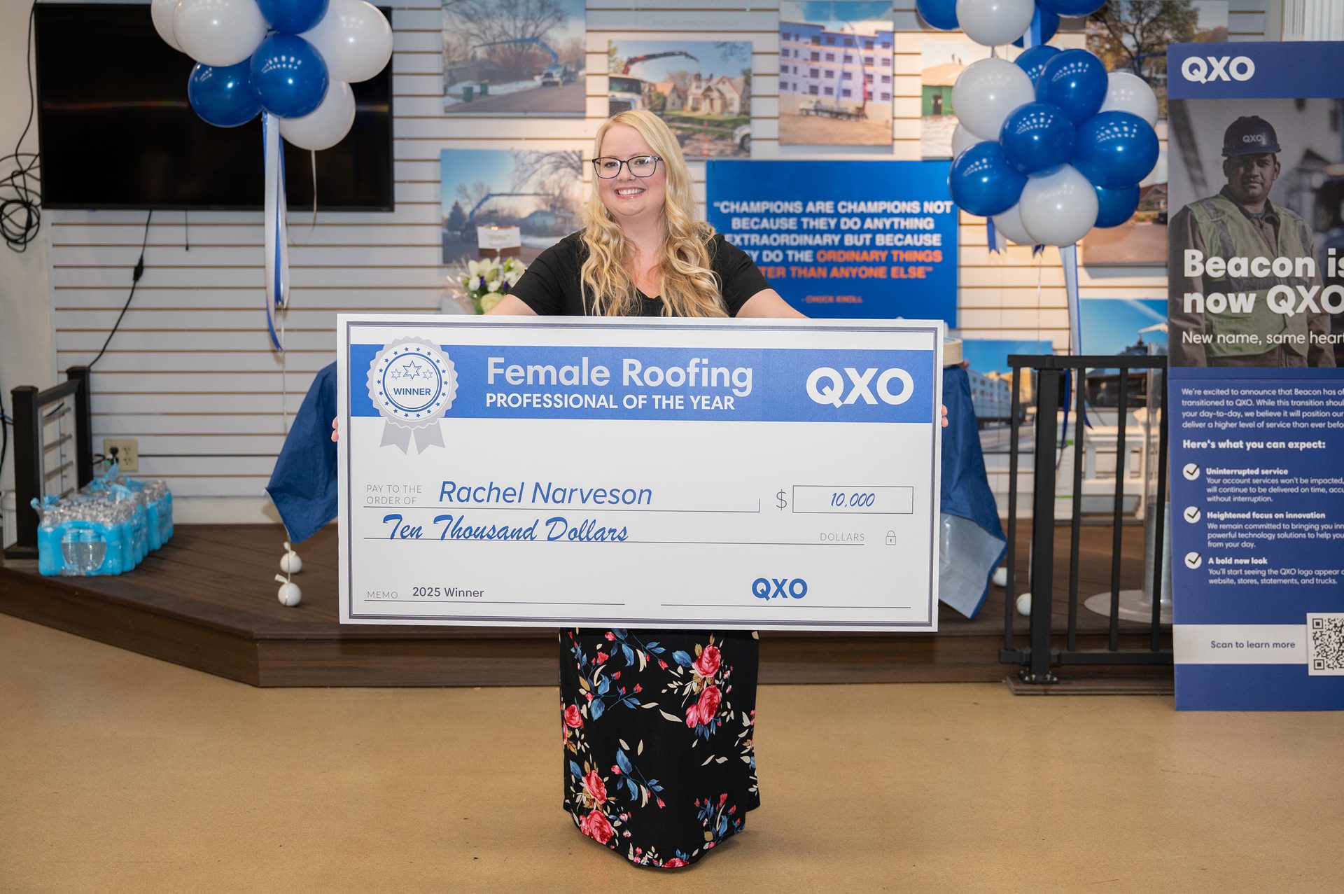 Smiling woman holding QXO's $10,000 "Female Roofing Professional of the Year" check.