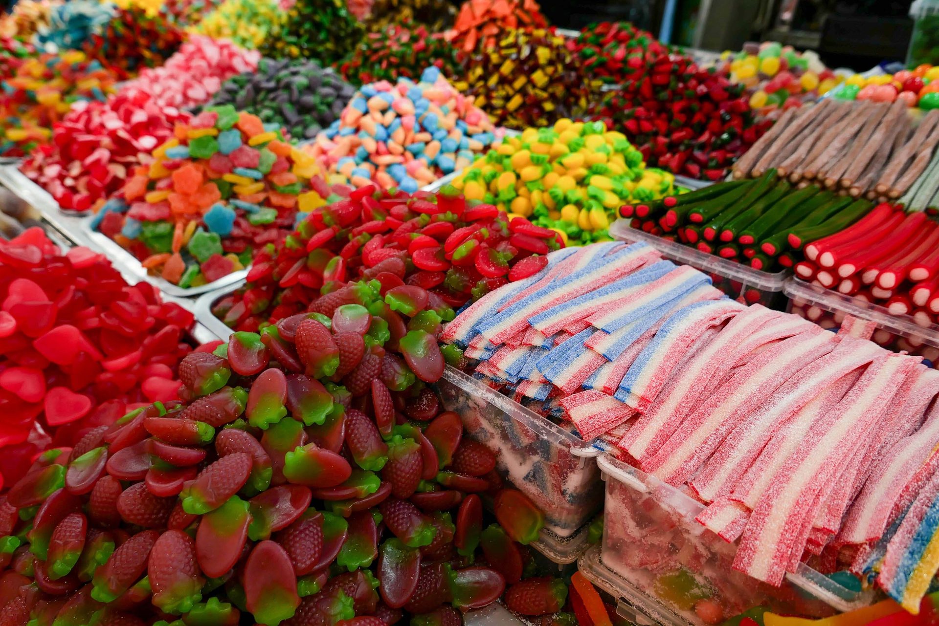 Colorful candy display with piles of gummies, sour belts, and other sweets.