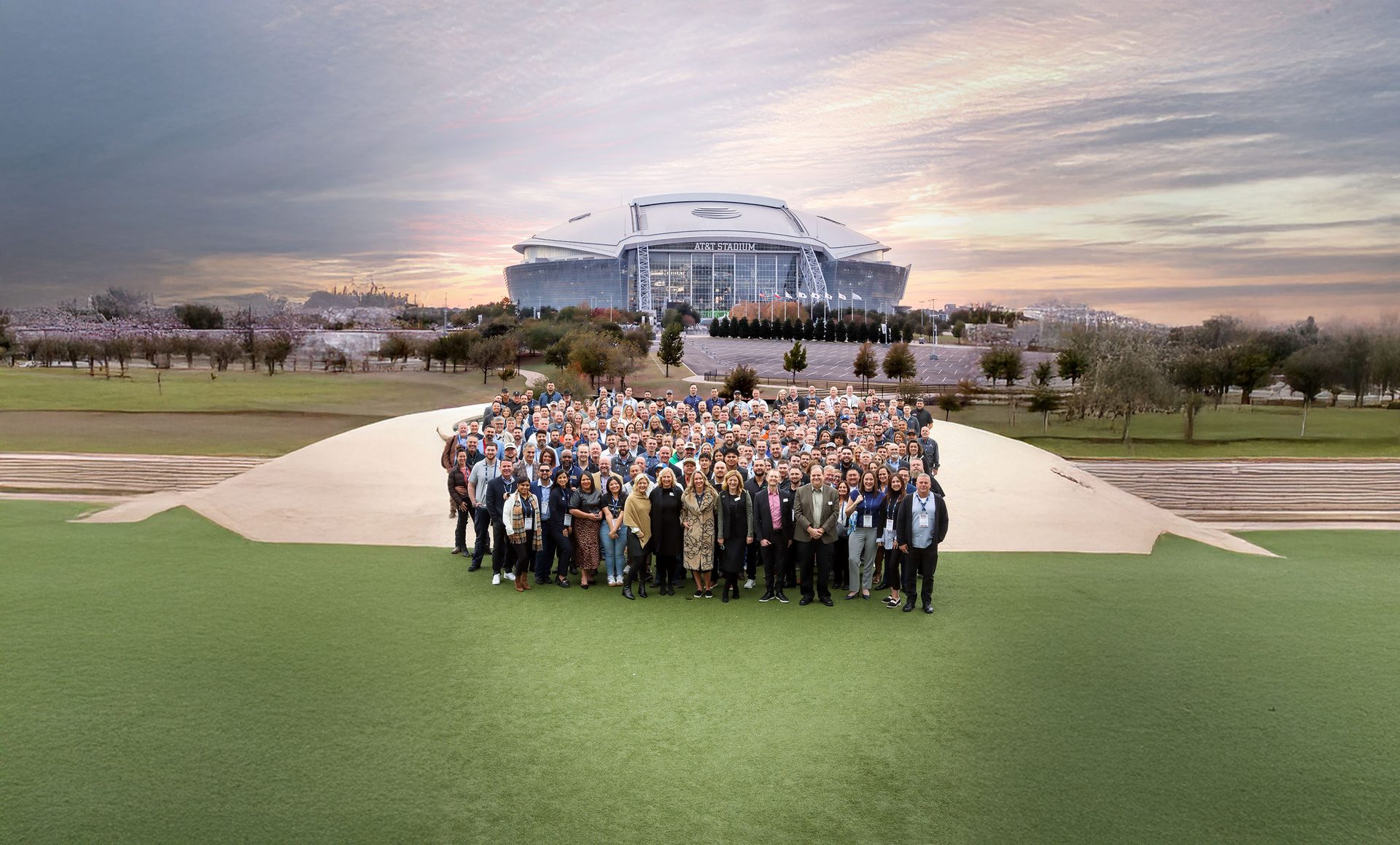 A large group of people posing outdoors with AT&T Stadium in the background.