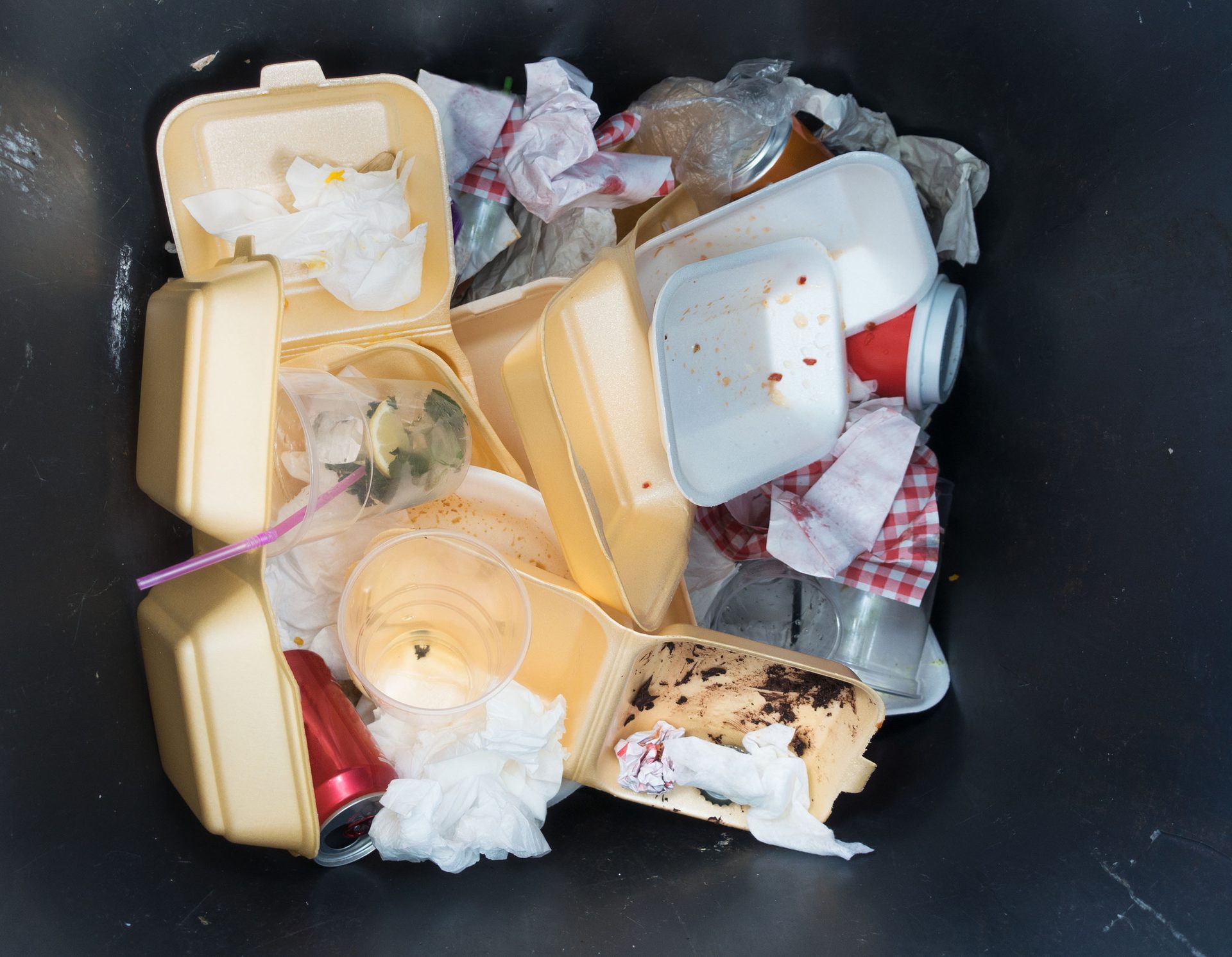 Trash bin filled with used fast food containers, cups, and napkins.