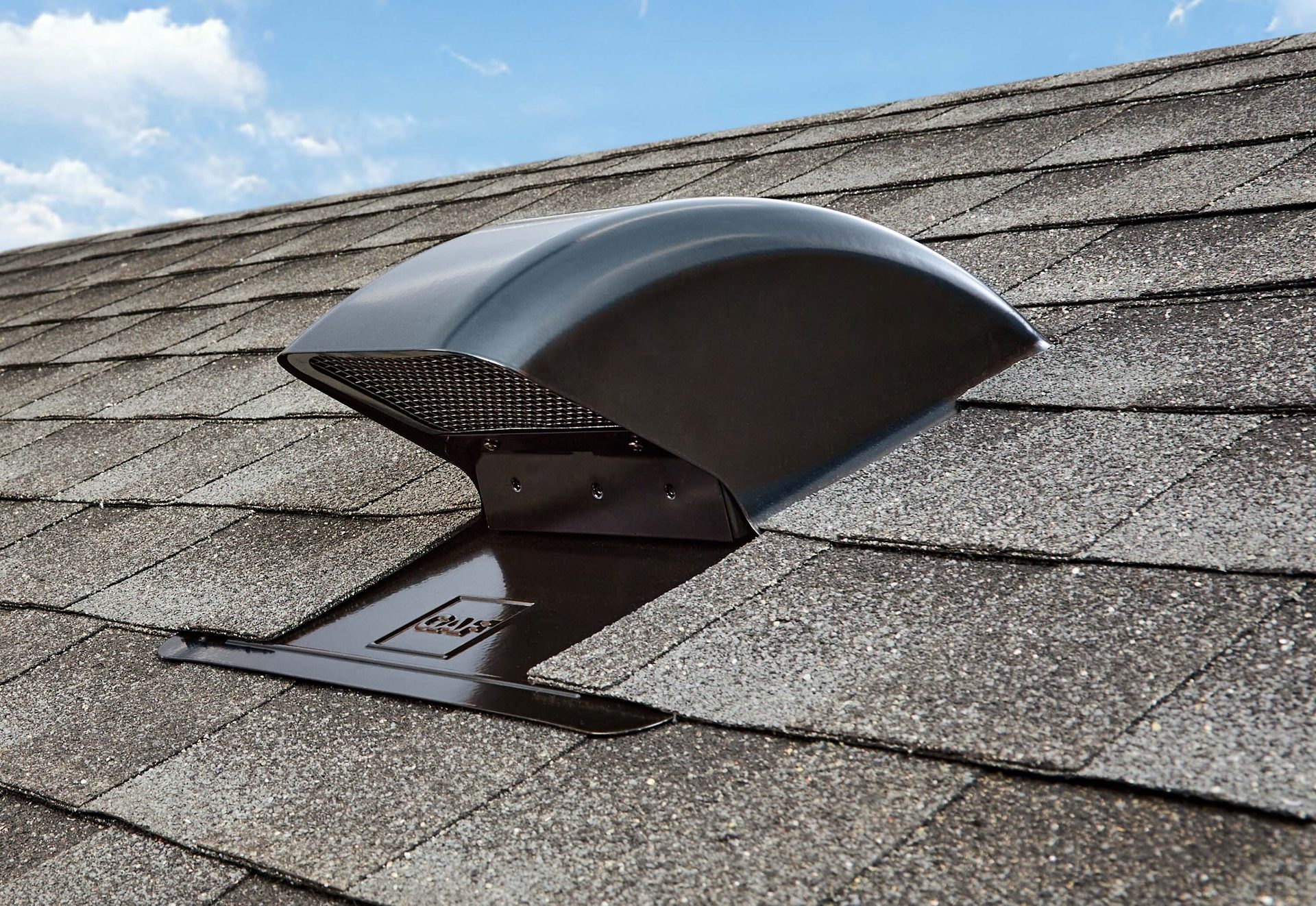 Dark gray roof vent on a gray shingle roof under a blue sky.