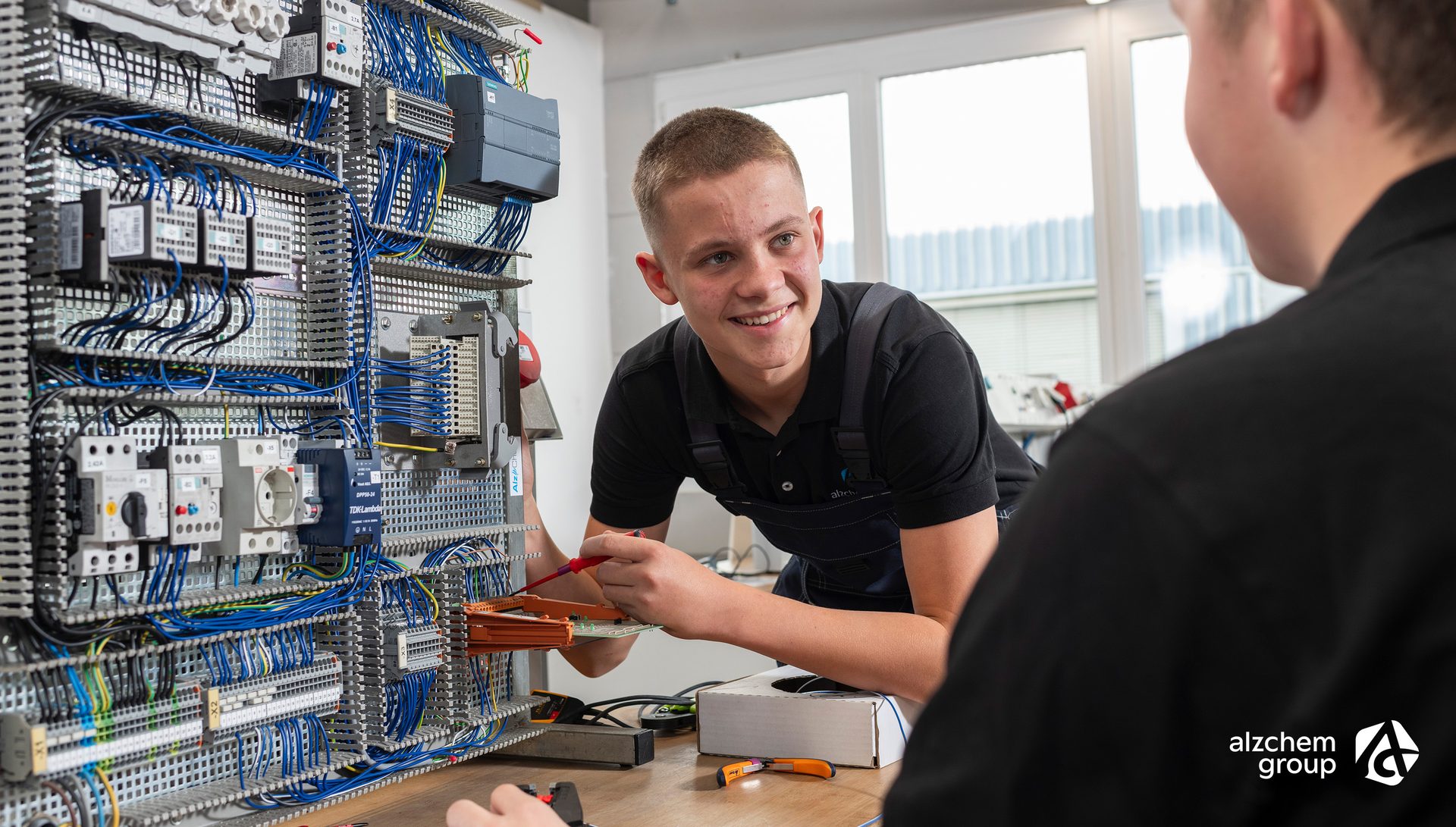 Two apprentices wiring an electrical cabinet.