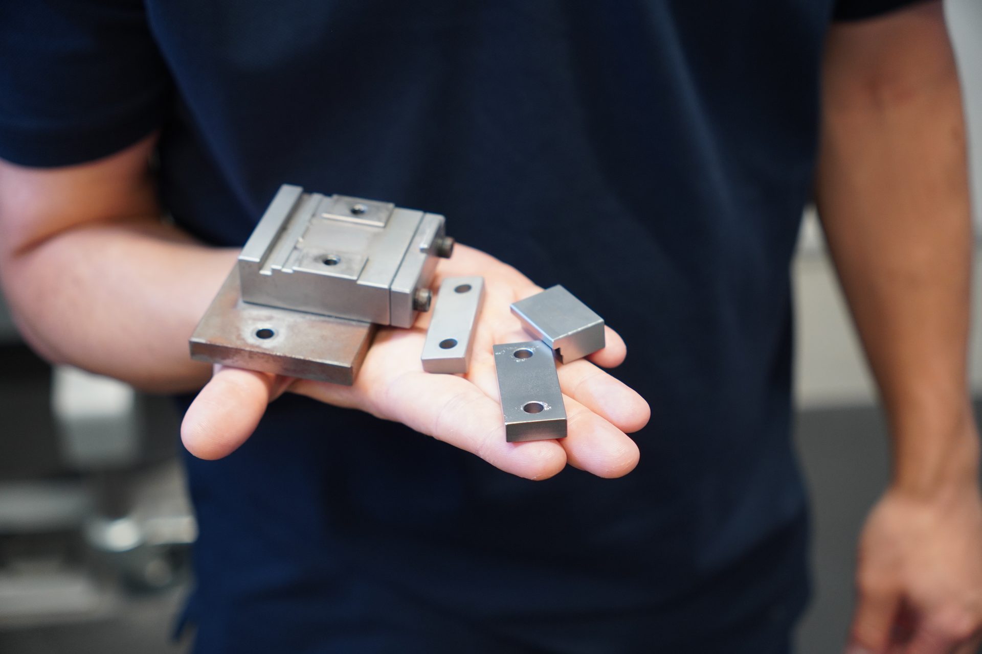 Person holding various precision metal machine parts in their open palm, highlighting manufacturing components.