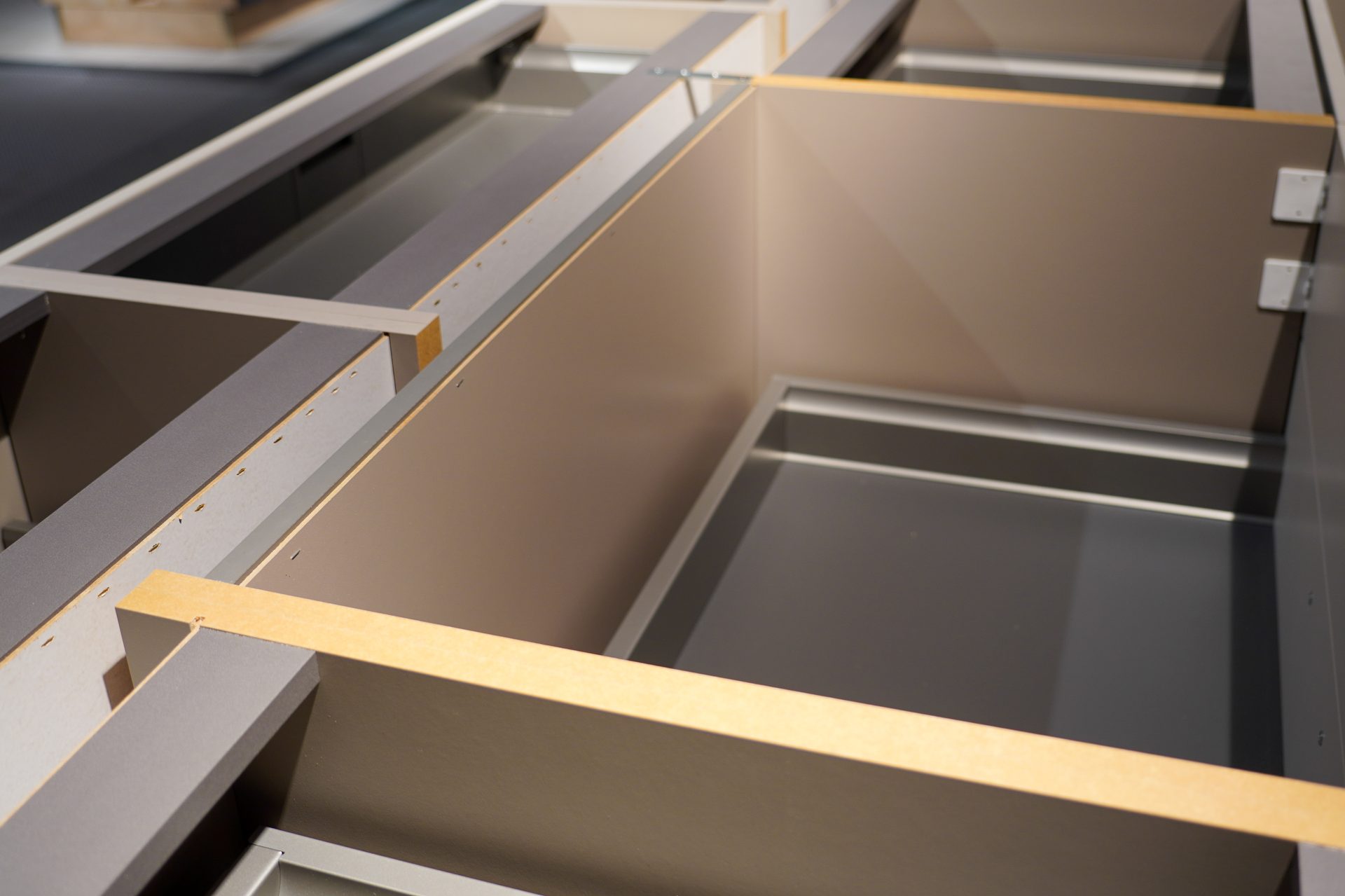Close-up of unfinished modular cabinet frames, showing various compartments and joint details.