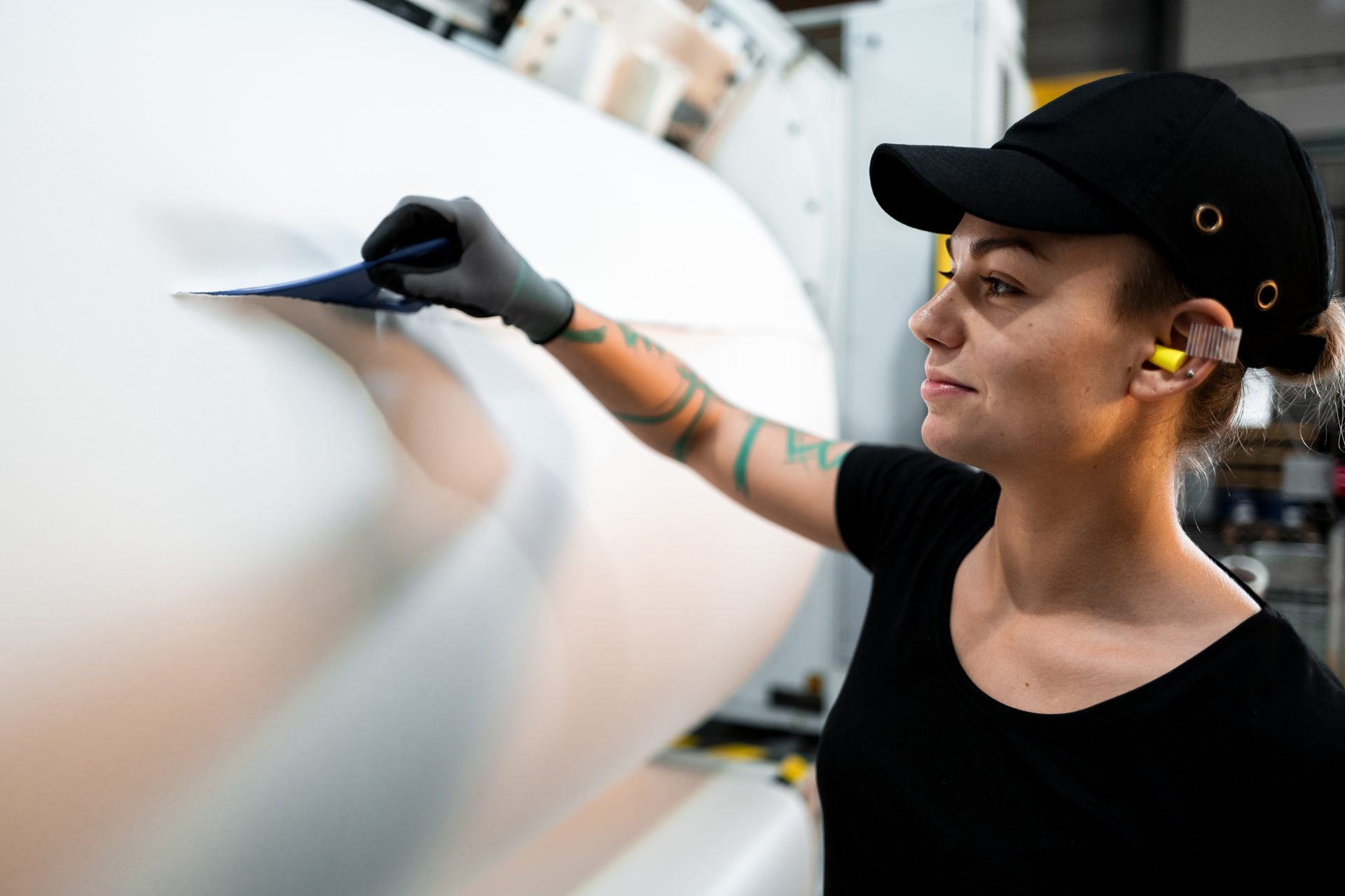 Woman worker smoothing a large roll of white material in a factory.