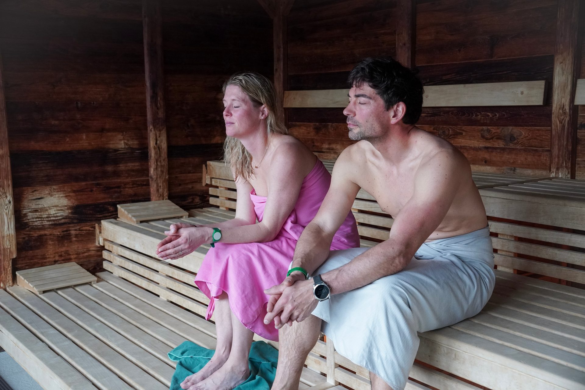 Couple relaxes in a sauna, eyes closed, enjoying the warmth.