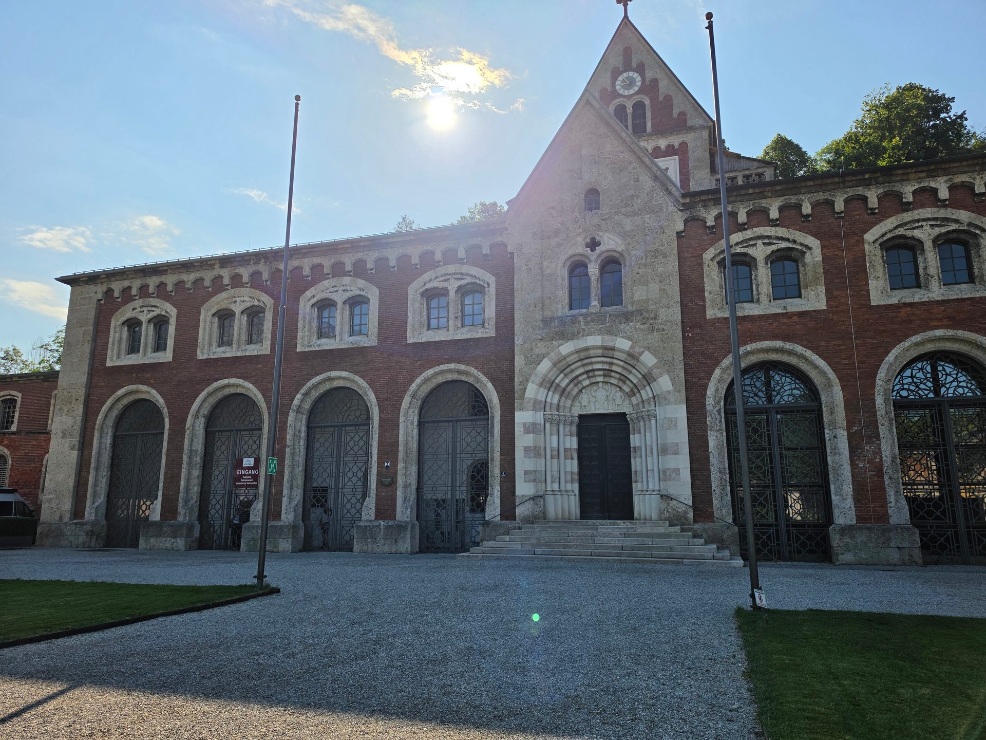 Historic brick and stone building with arched entrances, many windows, and a central gable with a clock.