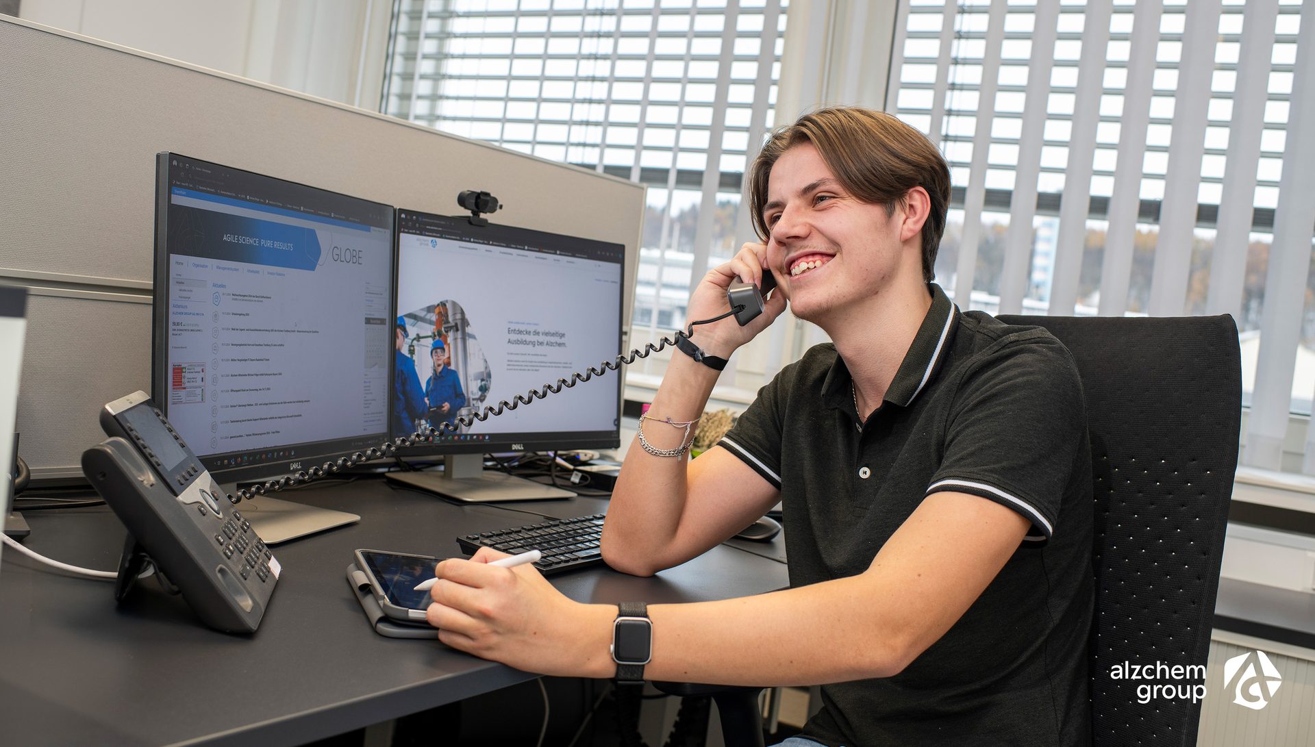 Smiling young man on phone at office desk.