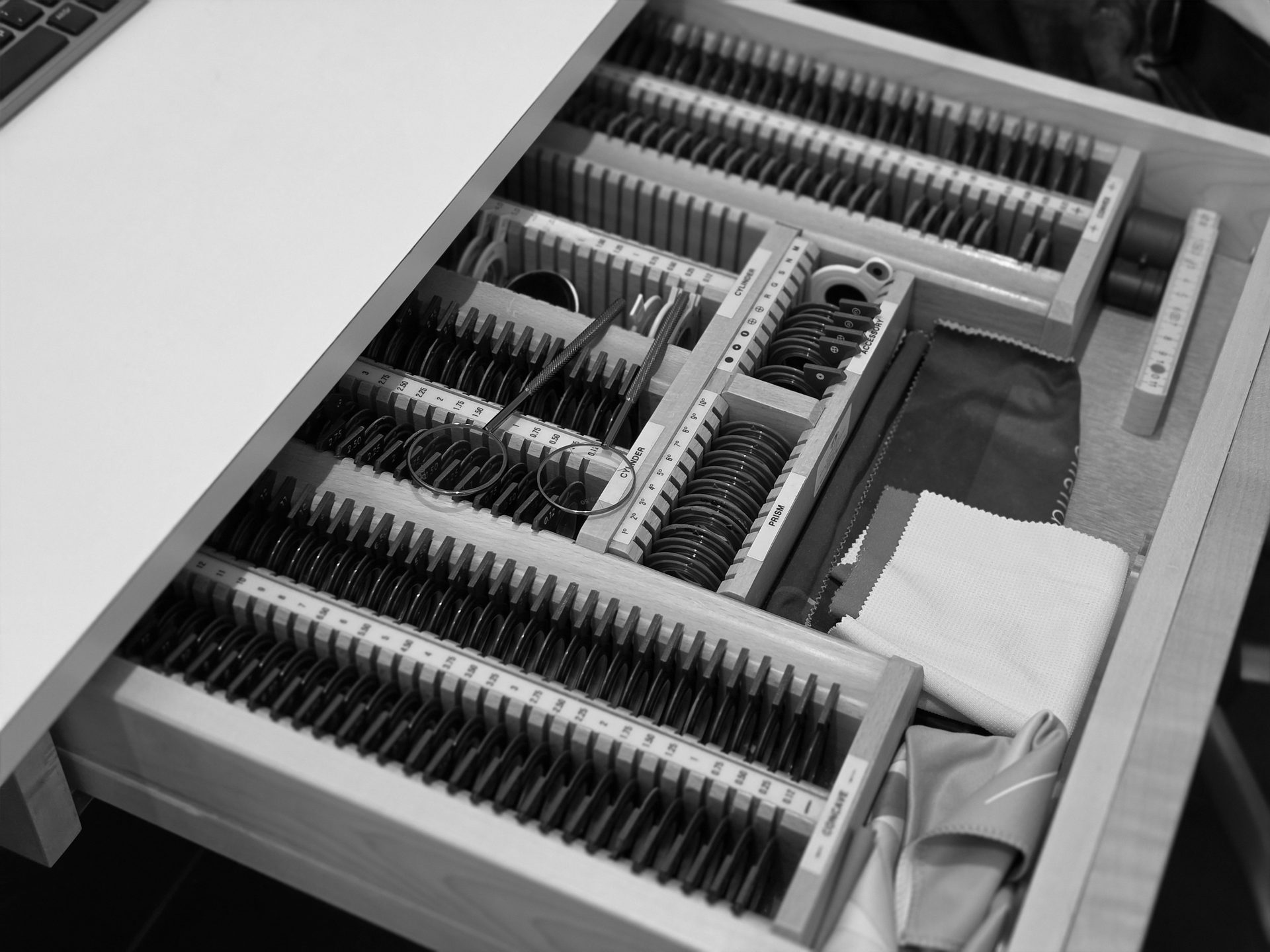 An opened drawer displays an ophthalmic trial lens set, trial frame, and cleaning cloths.
