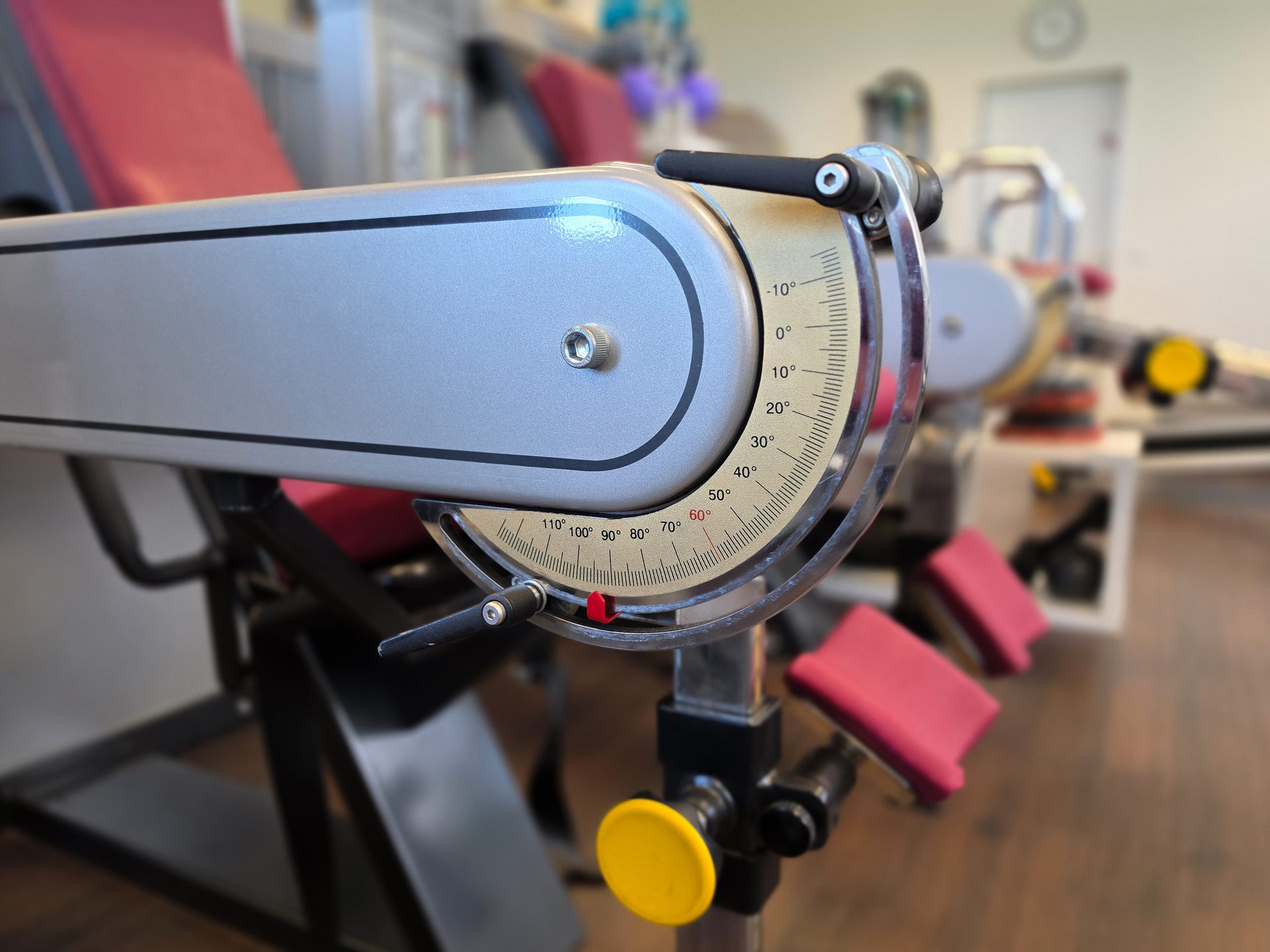 Close-up of a gym machine's adjustment mechanism, showing an angle dial and a gray arm.