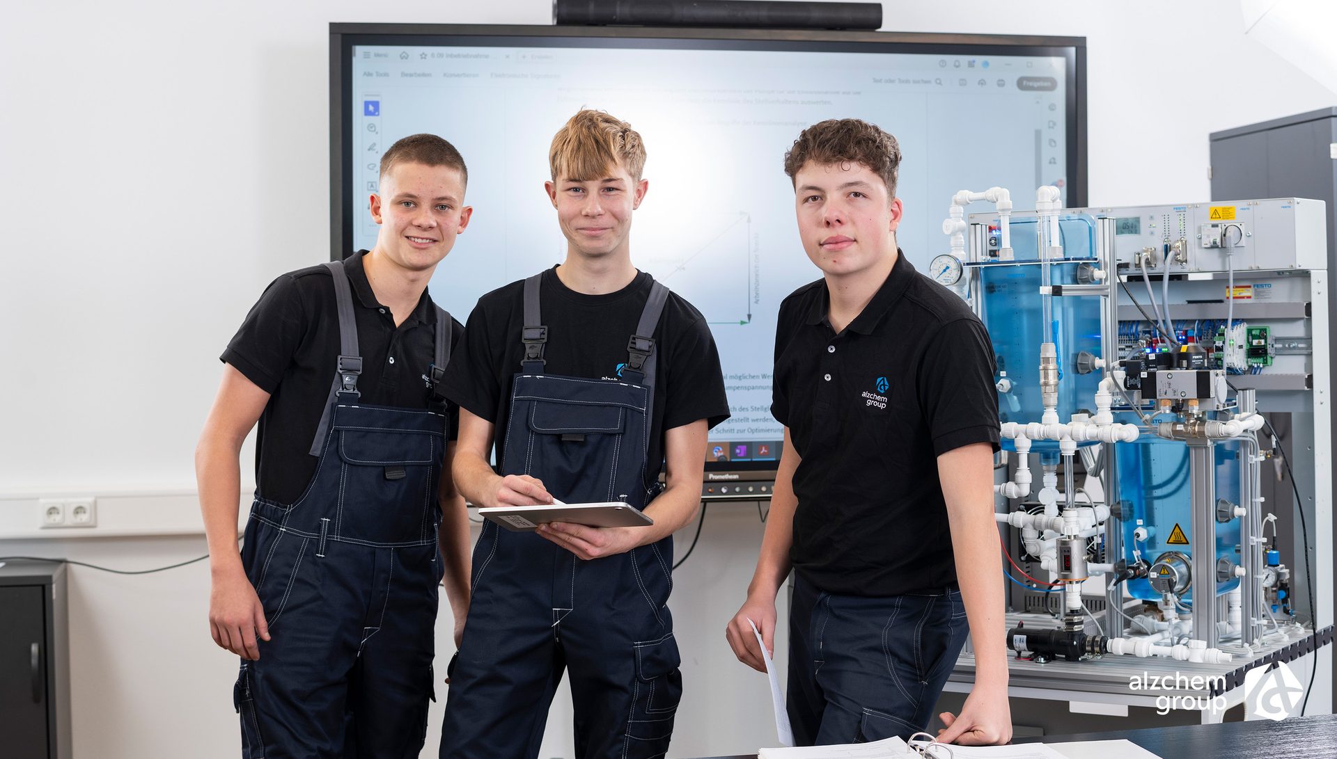Three Alzchem trainees with technical equipment and screen in classroom.