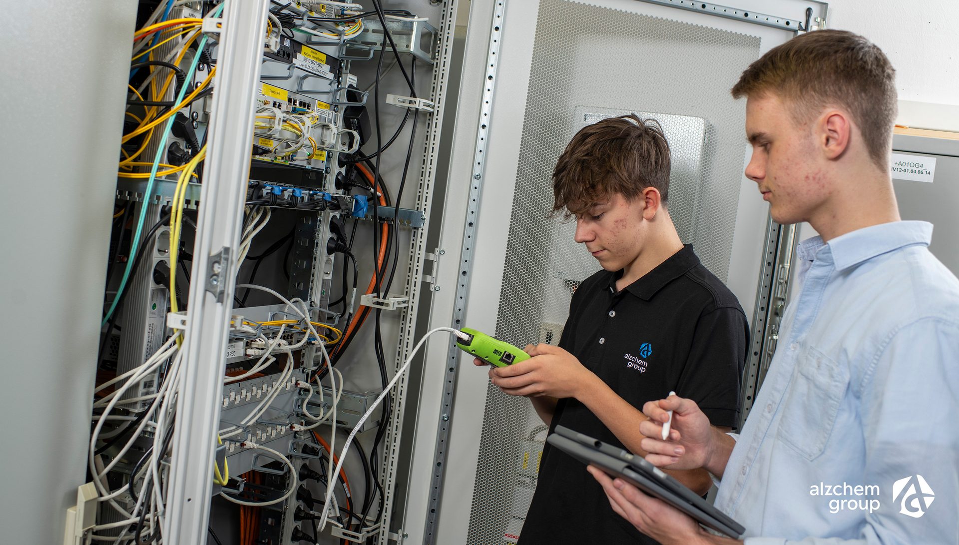 Alzchem trainees working on network rack with tools.