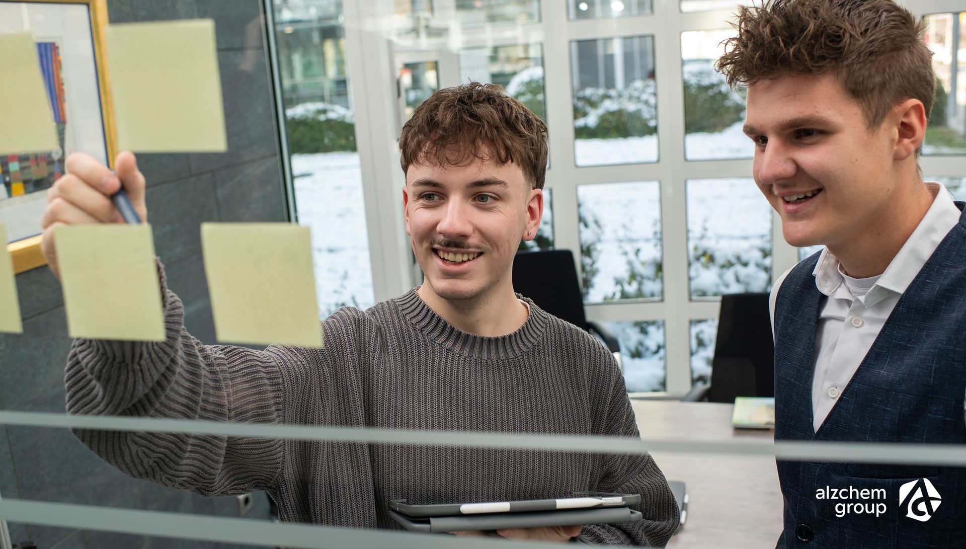 Two smiling colleagues brainstorming with sticky notes.