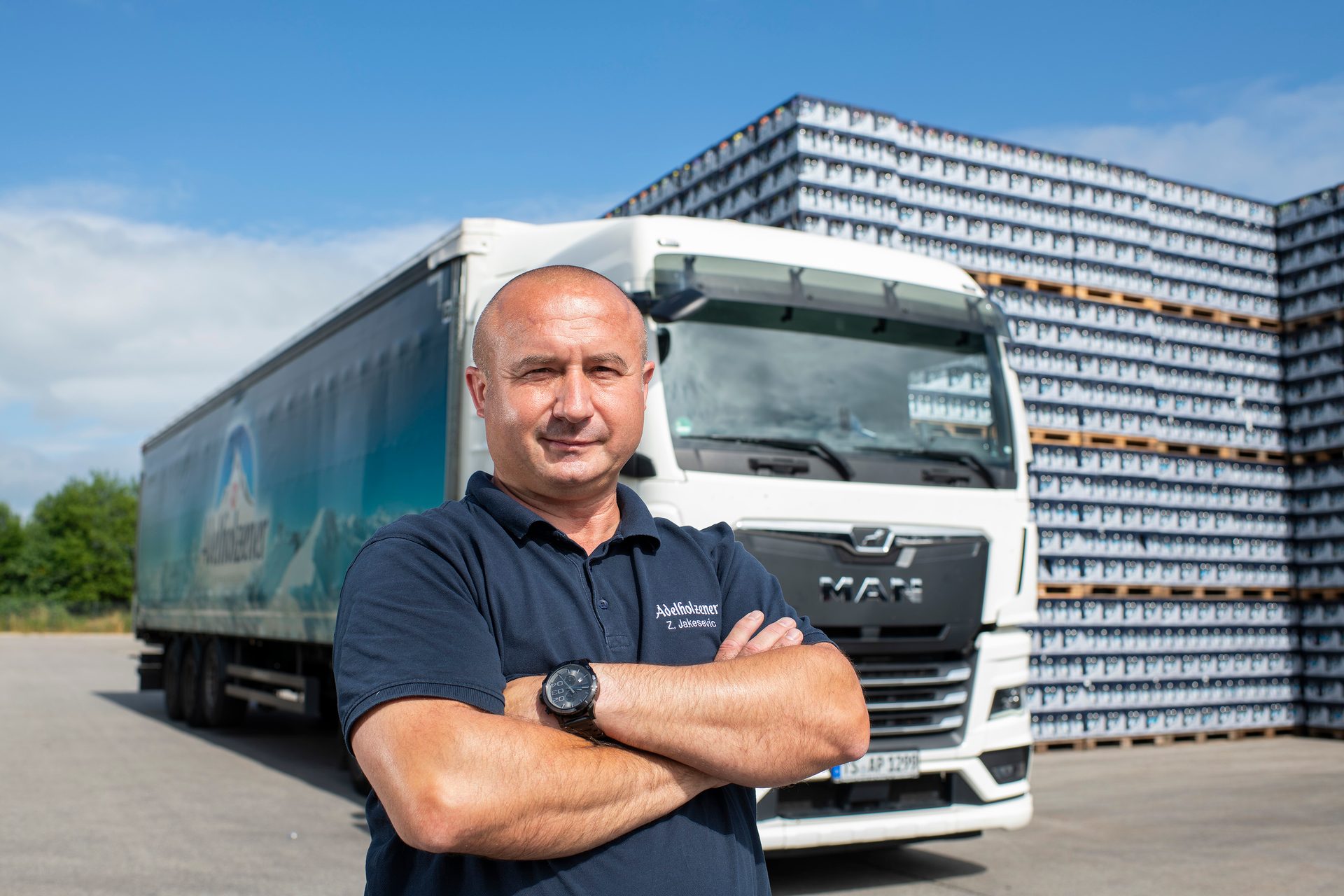 Man in Adelholzener polo shirt with truck and product stacks.