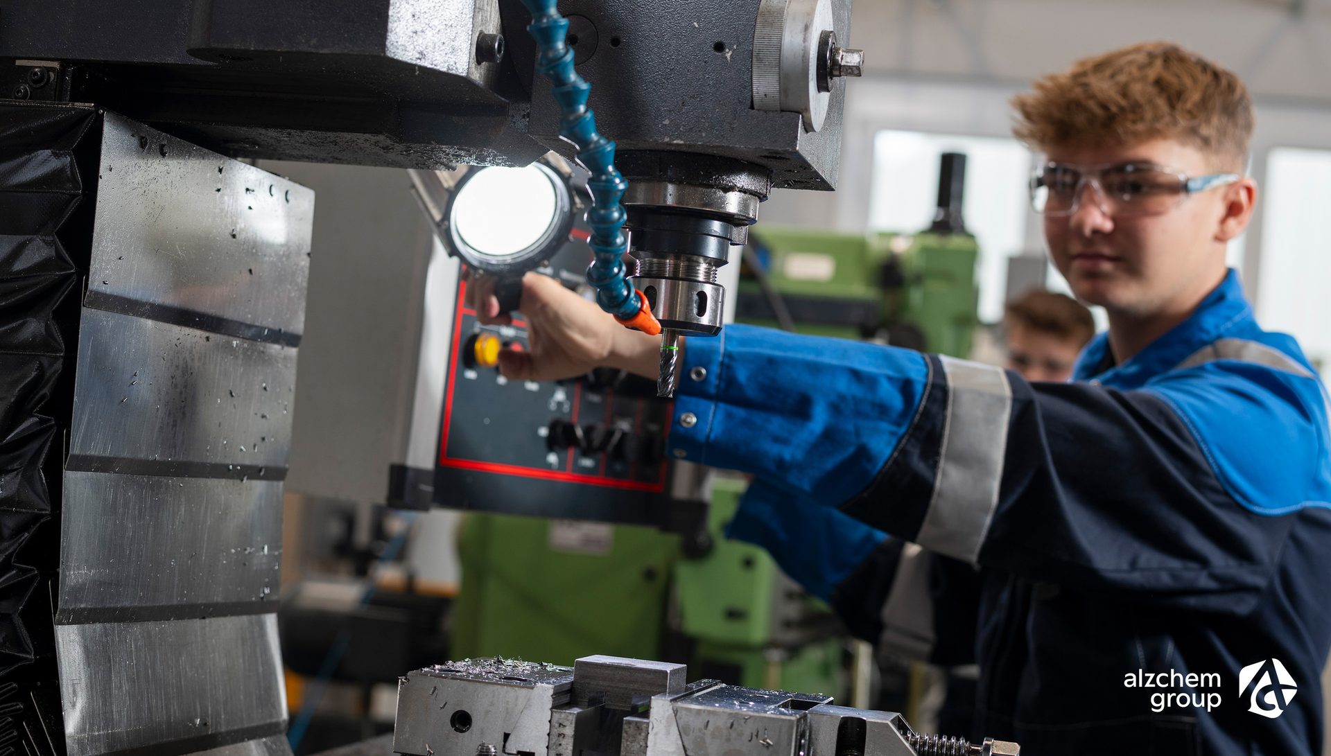 Young worker in safety glasses operating machinery.