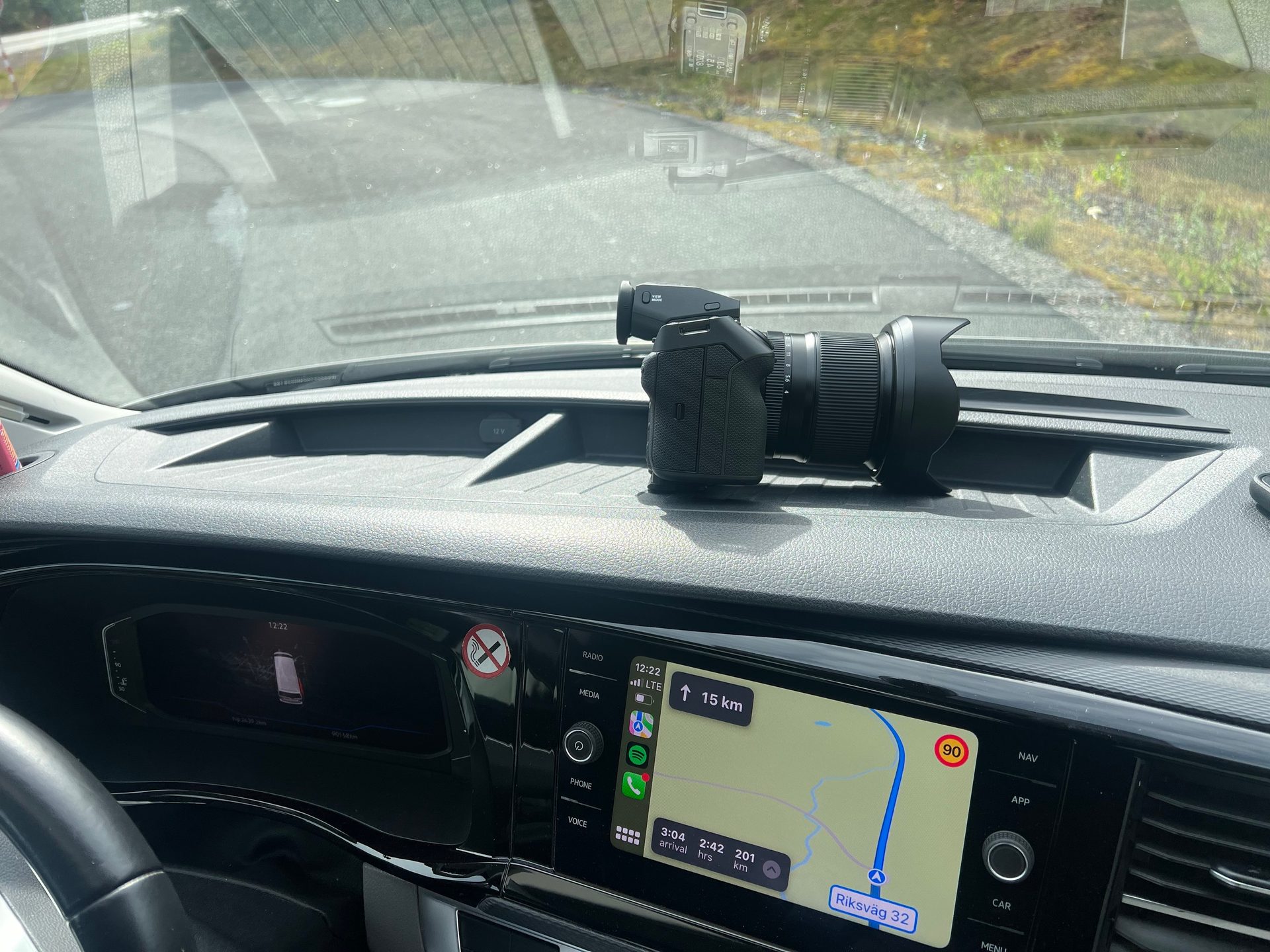 A camera rests on a car dashboard with a navigation screen displaying a map and route information.
