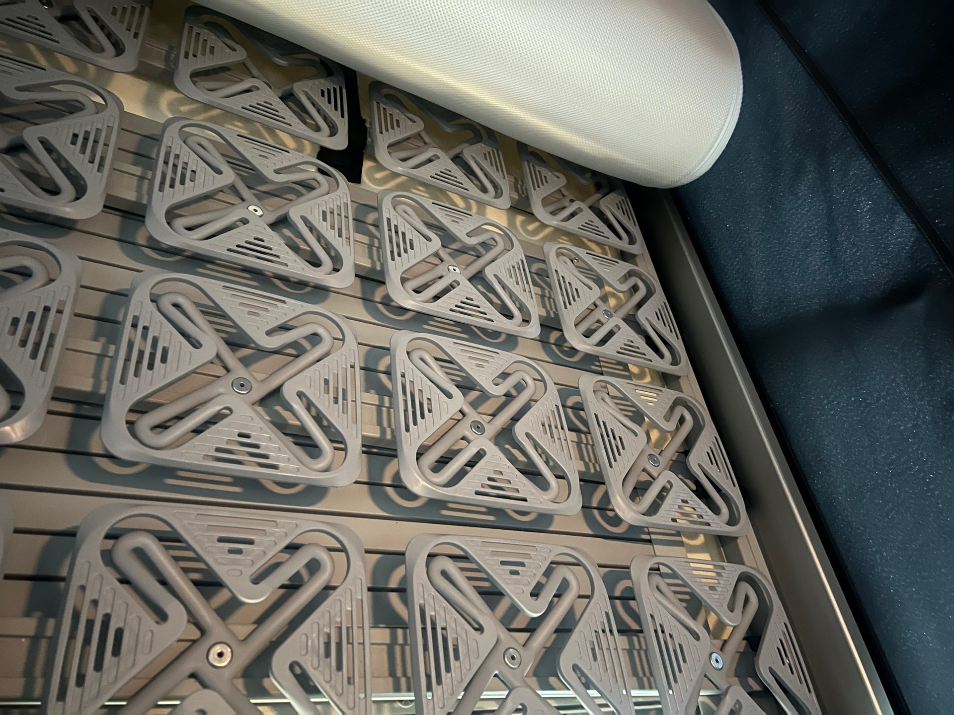 Gray, square-shaped spring elements of a bed base, supporting a white mattress.