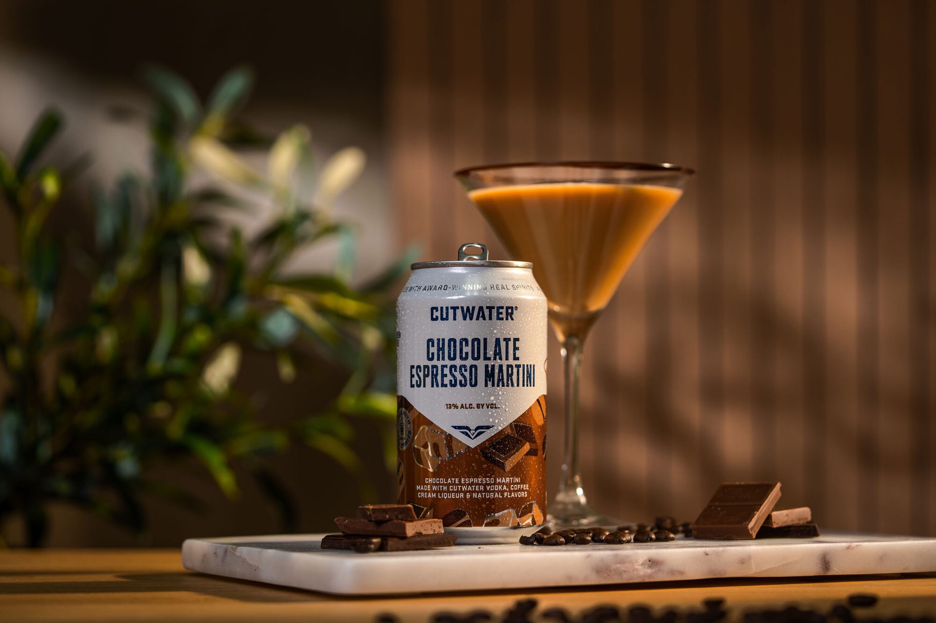 Cutwater Chocolate Espresso Martini can, served in a glass with chocolate and coffee beans on a marble board.