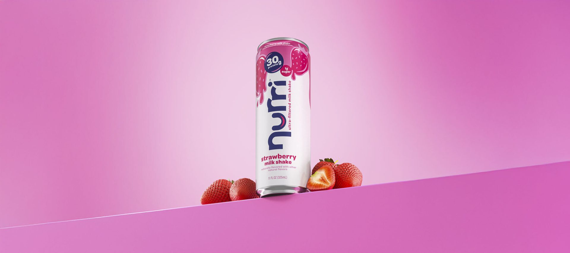 A "nurri" strawberry milk shake can (30g protein, 1g sugar) and fresh strawberries on a pink background.