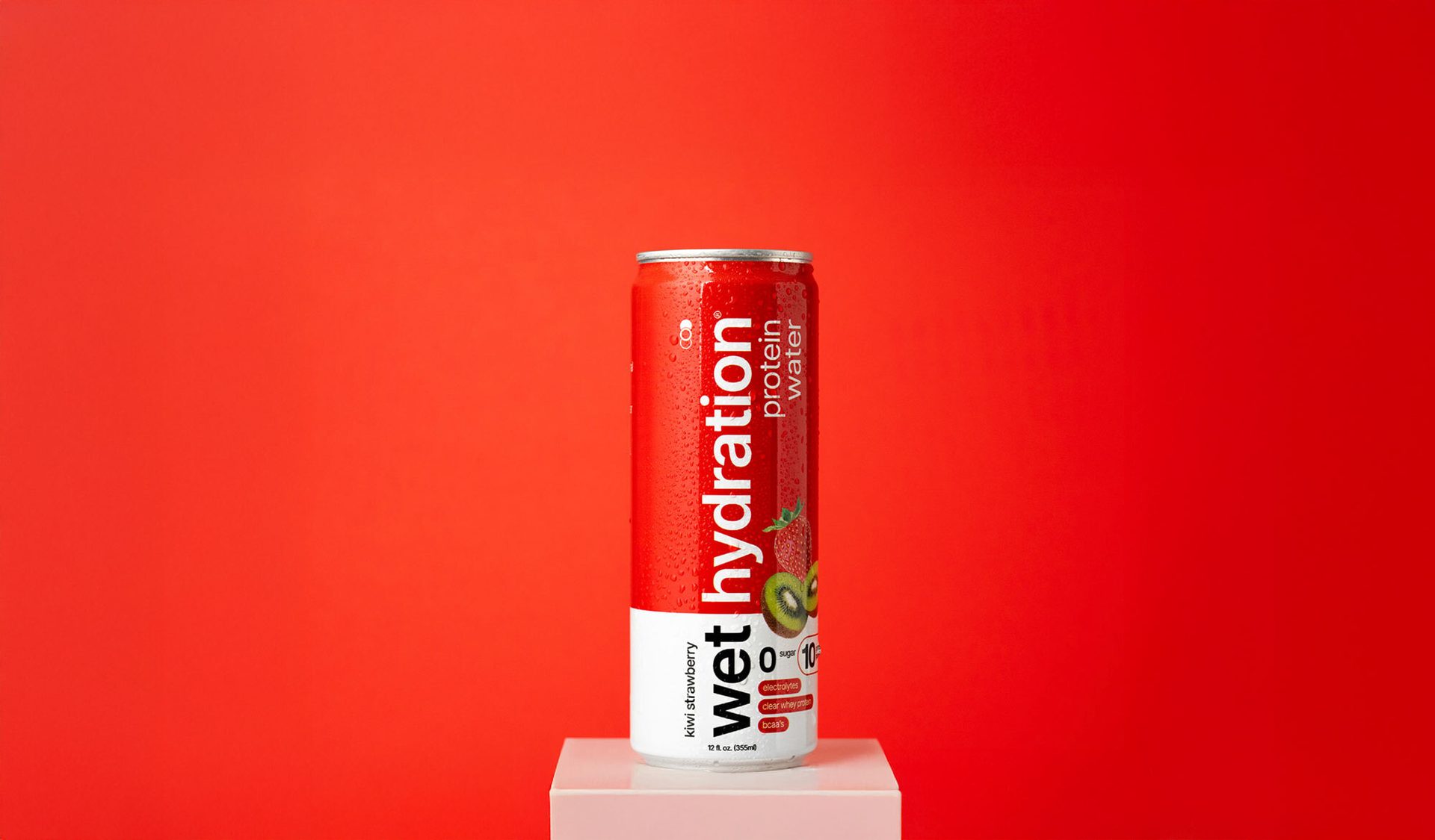 Red "Wet Hydration" kiwi strawberry protein water can with water droplets on a white block against a red background.