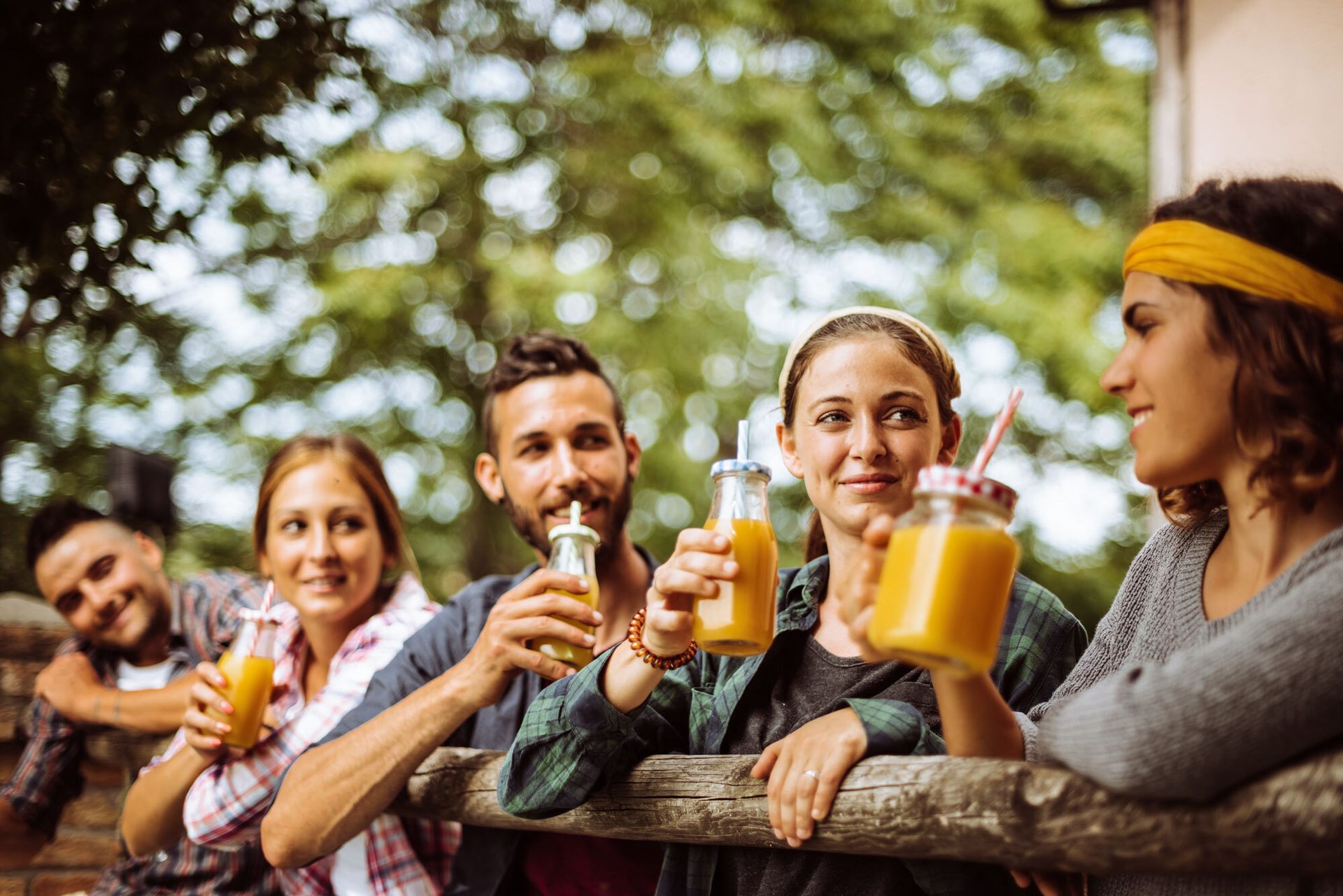 Friends outdoors smiling and holding drinks.