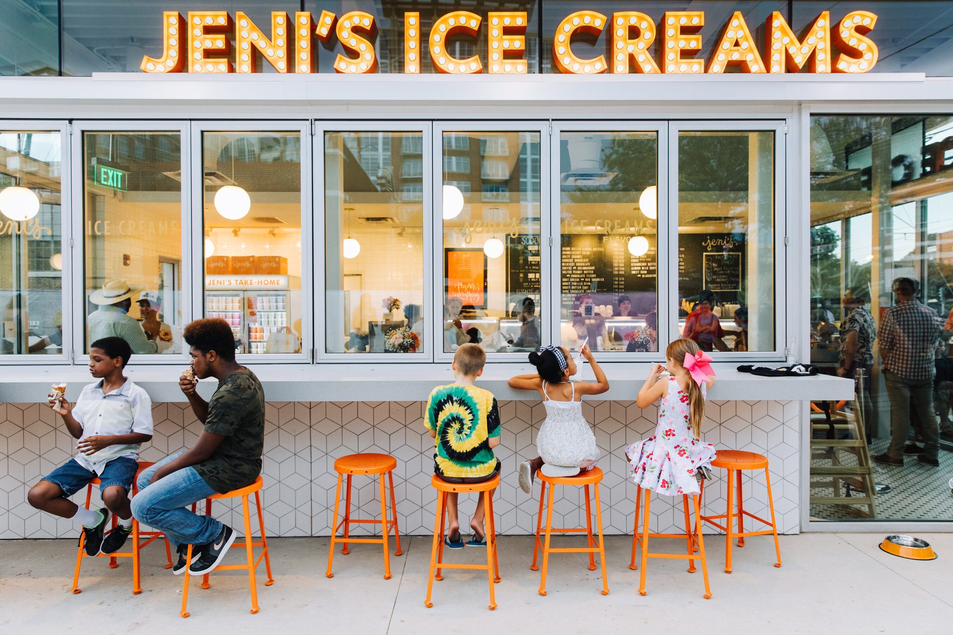 Kids and young adults eat ice cream at an outdoor counter of Jeni's Ice Creams shop.